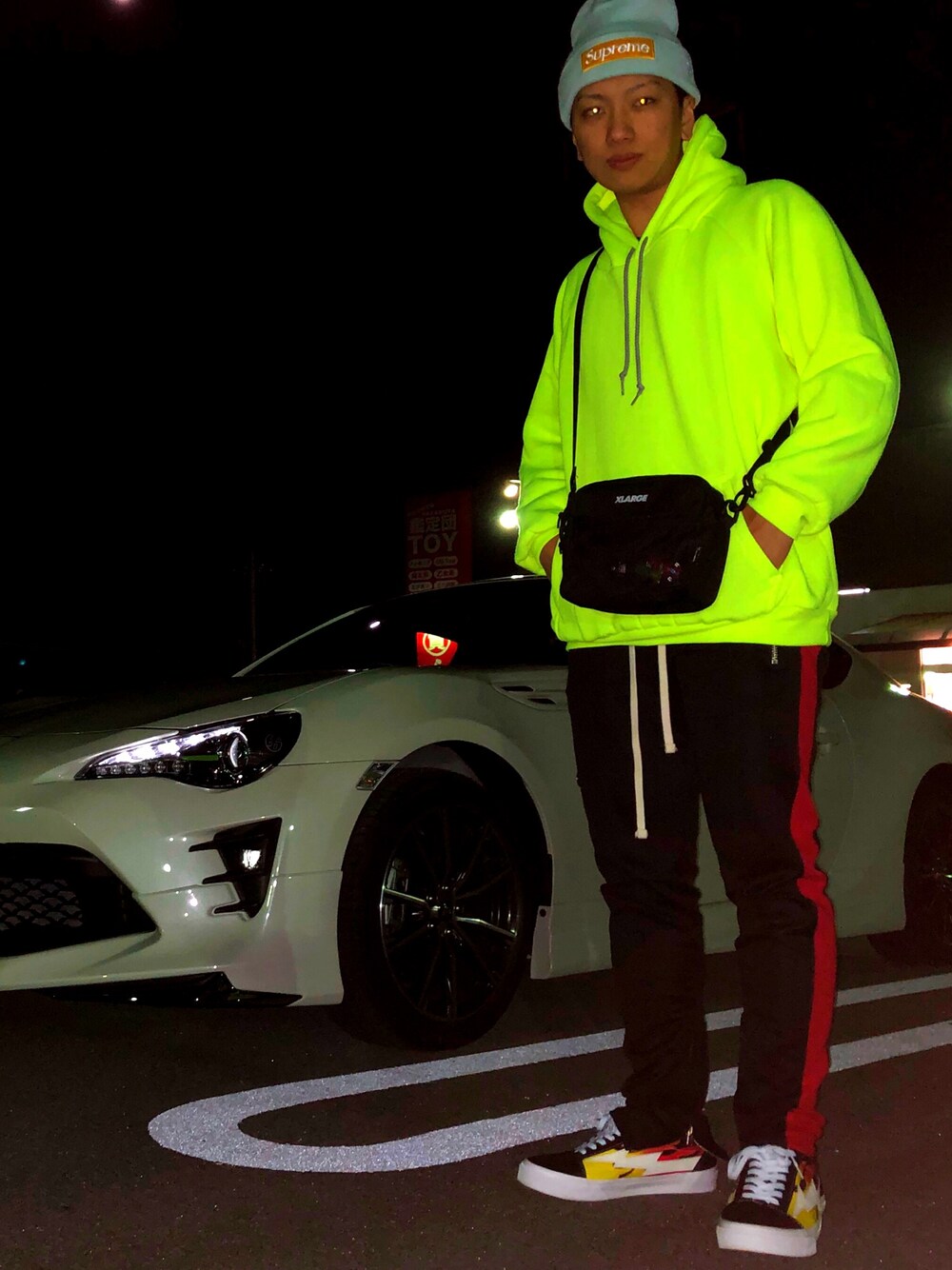 グリーン系のパーカー、ブラック系のショルダーバッグ、ブラック系のパンツを着用したメンズの冬コーディネートの1枚目の写真