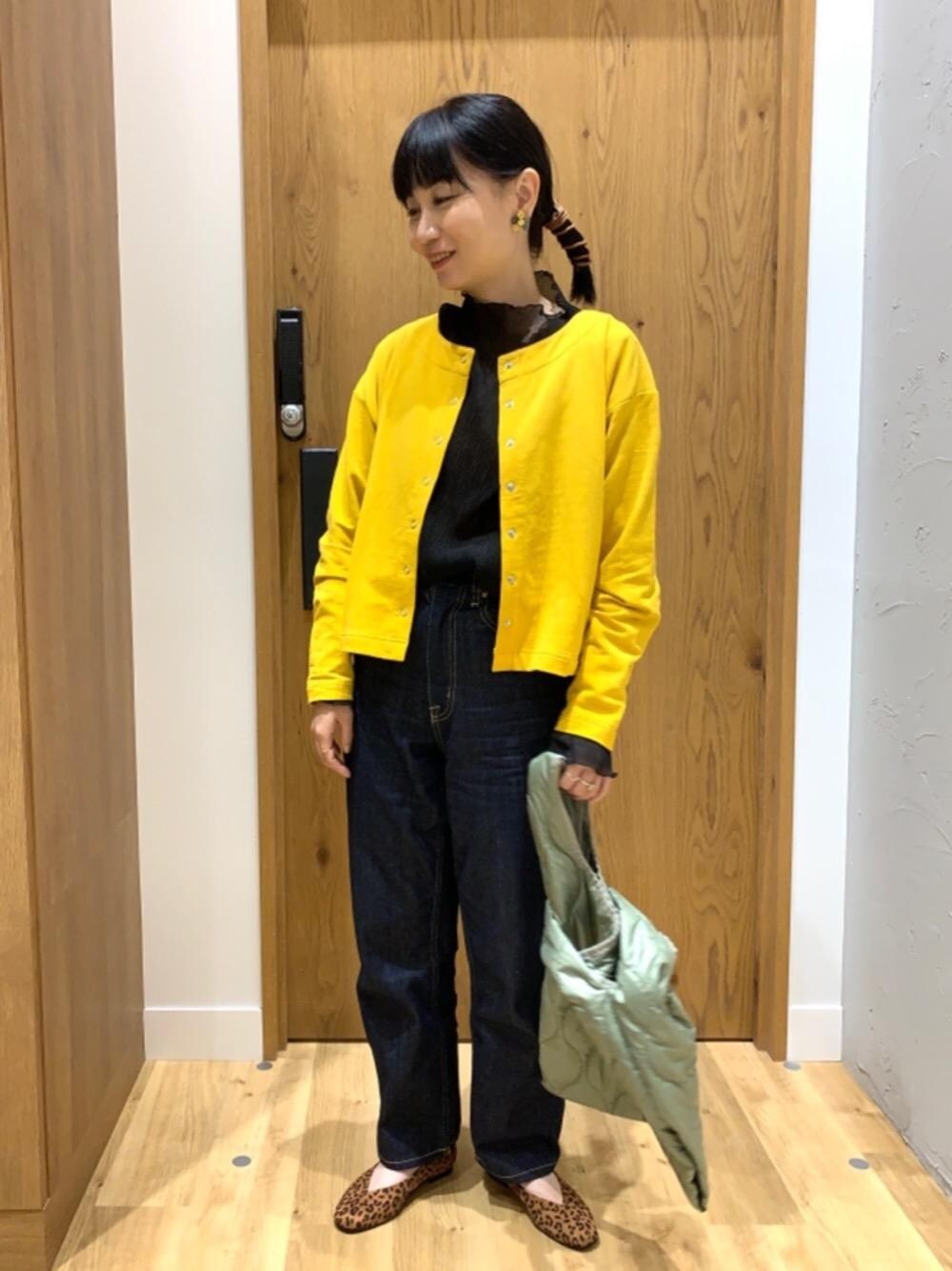 ブルー系のデニムパンツ、イエロー系のカーディガン/ボレロ、グリーン系のトートバッグを着用したレディースの秋コーディネートの1枚目の写真