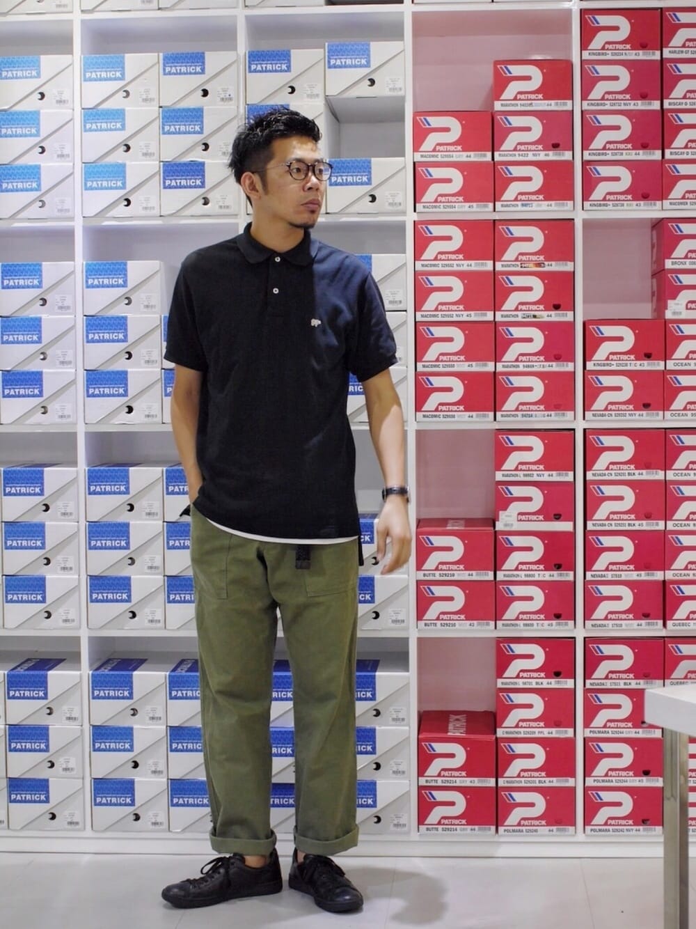 ブラック系のポロシャツ、グリーン系のその他パンツ、ブラック系のスニーカーを着用したメンズの夏コーディネートの1枚目の写真