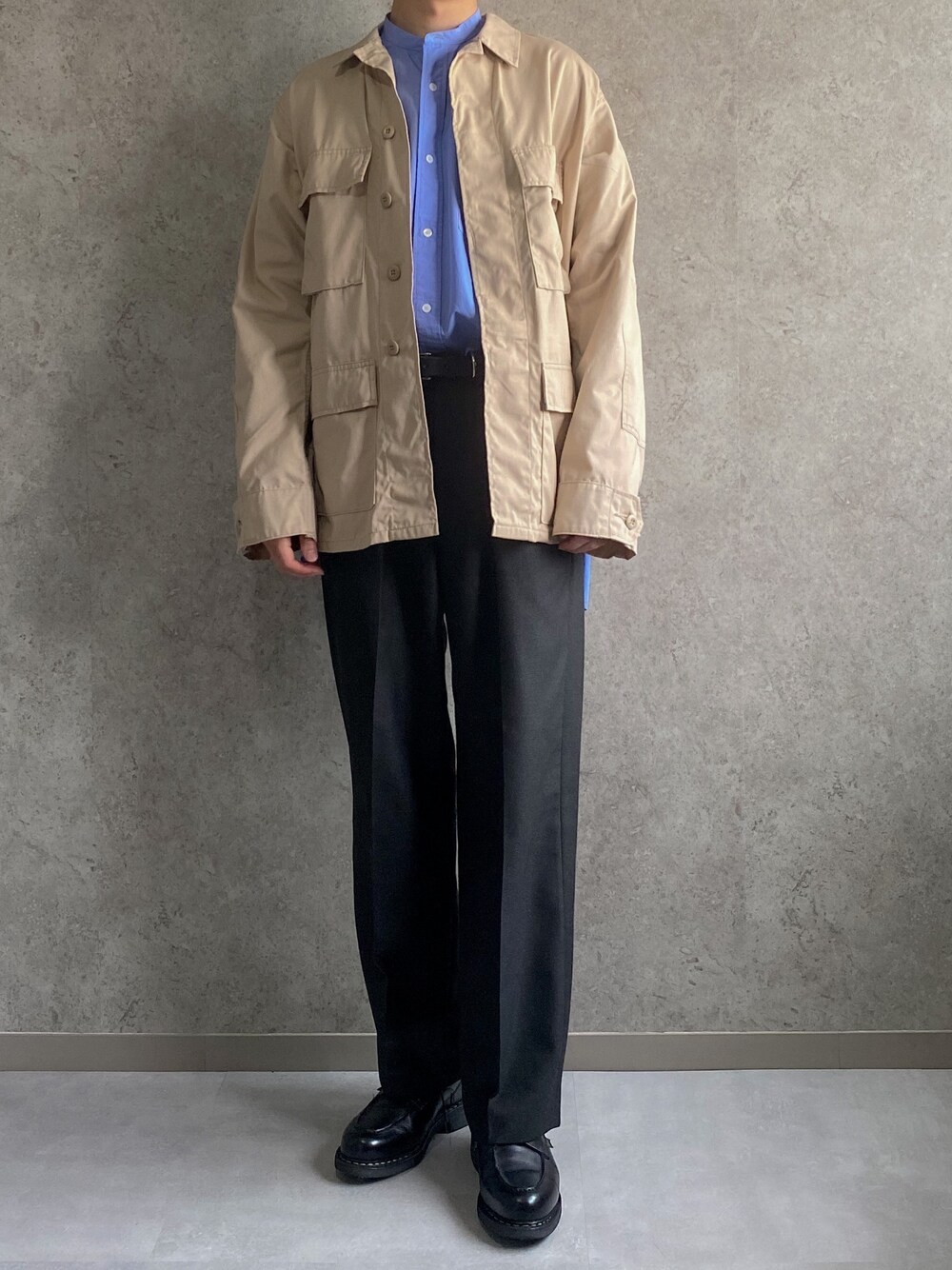 ブラウン系のミリタリージャケット、ブルー系のシャツ/ブラウス、グレー系のスラックスを着用したメンズの春コーディネートの1枚目の写真