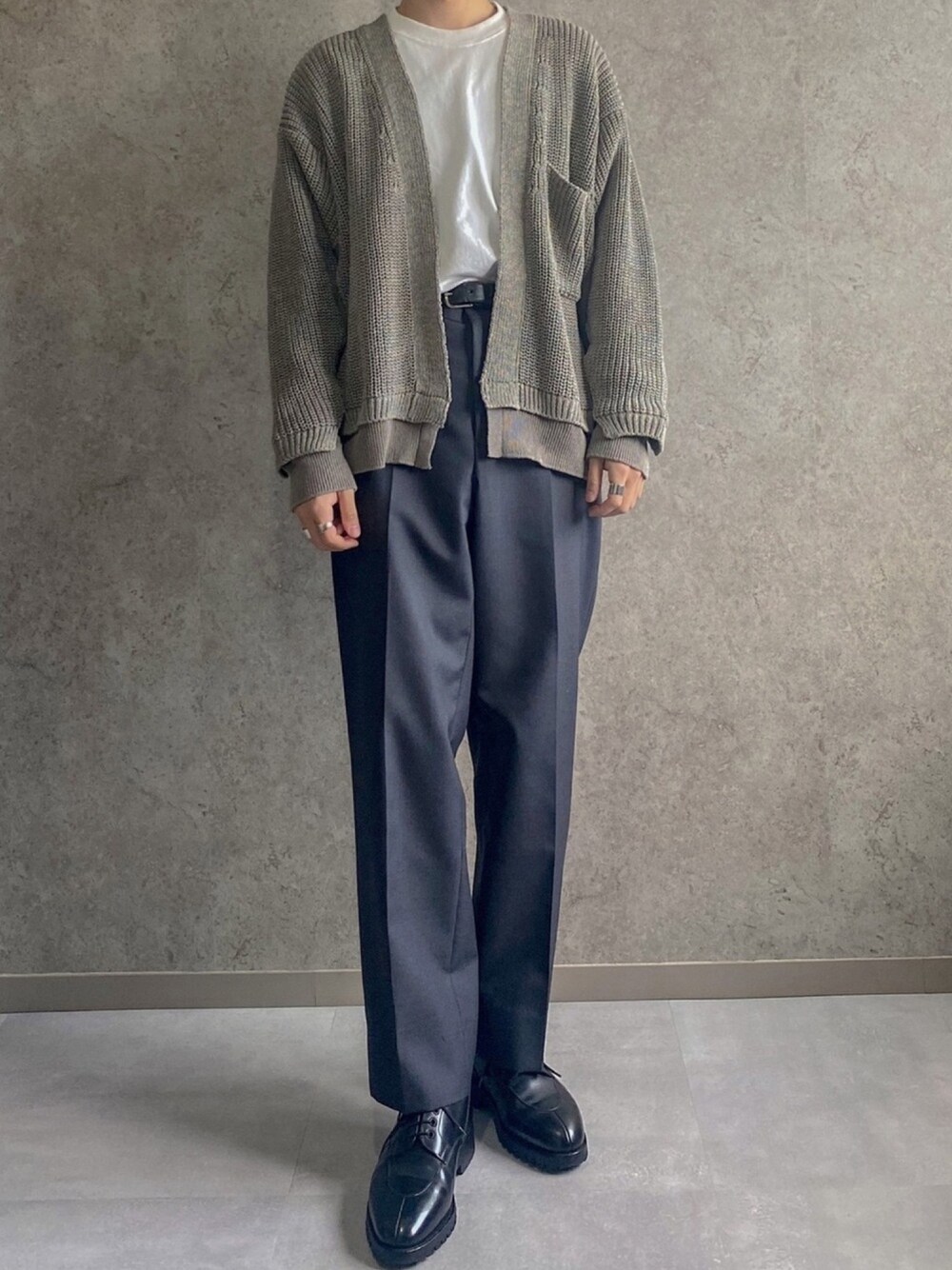 グリーン系のカーディガン/ボレロ、ブラック系のドレスシューズ、グレー系のスラックスを着用したメンズの春コーディネートの1枚目の写真