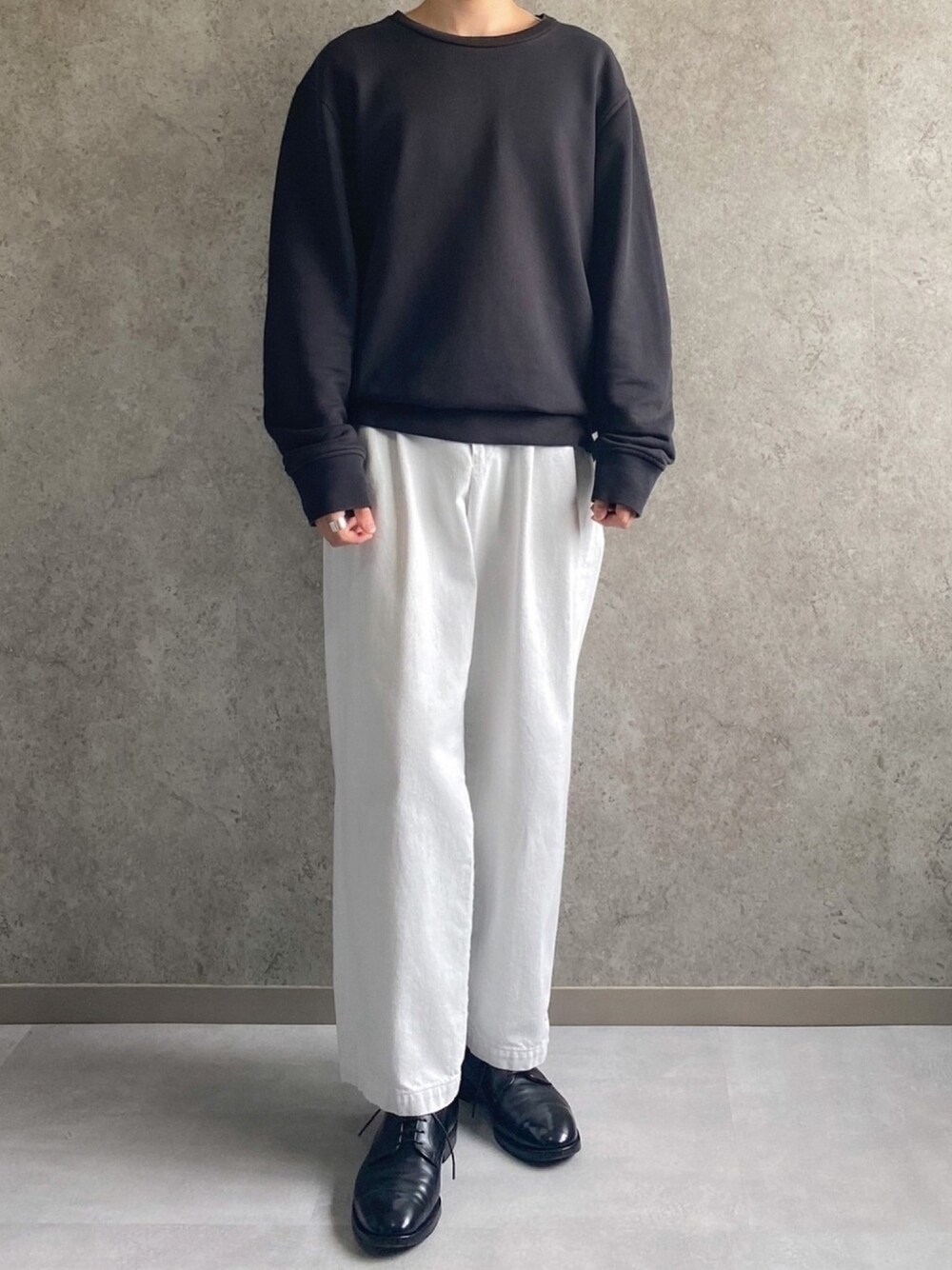 ブラック系のスウェット、ホワイト系のデニムパンツ、ブラック系のドレスシューズを着用したメンズの春コーディネートの1枚目の写真