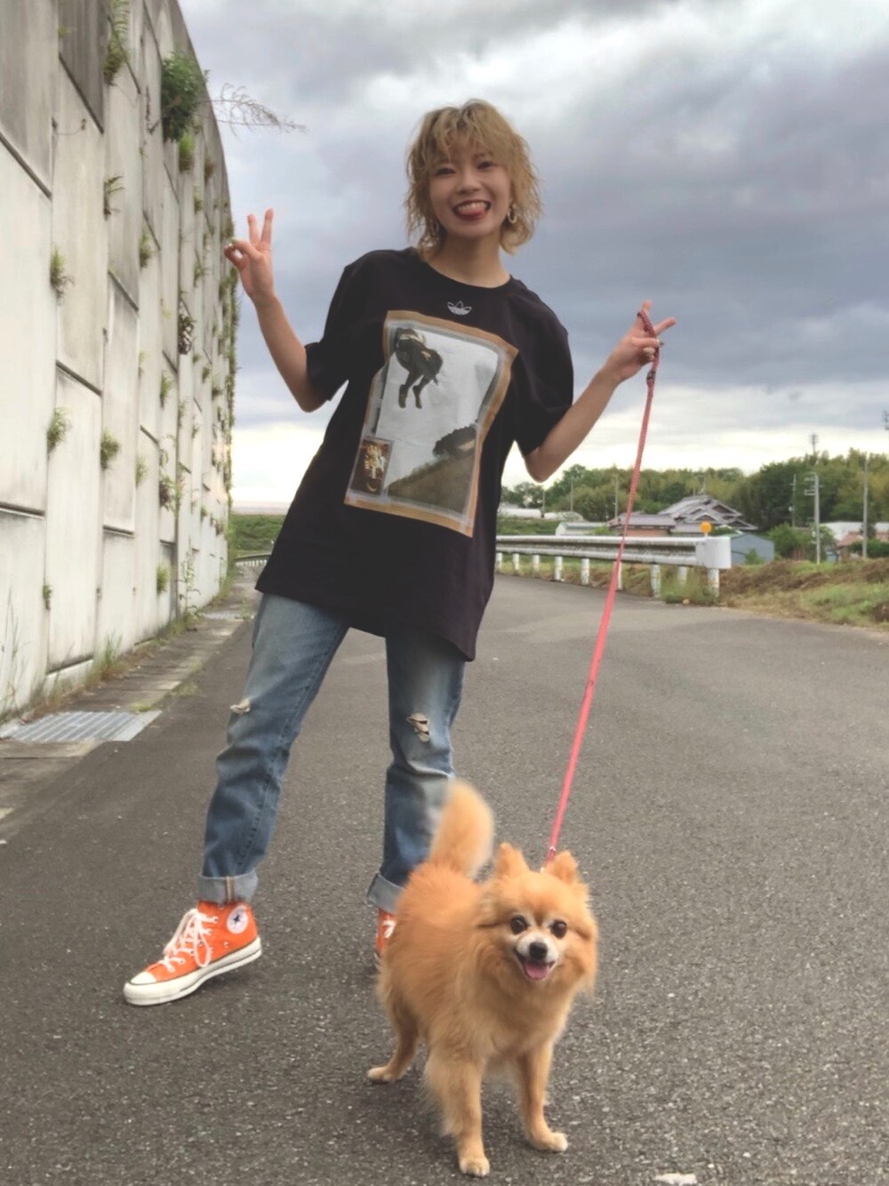 ブラック系のTシャツ/カットソー、ブルー系のデニムパンツ、オレンジ系のスニーカーを着用したレディースの春コーディネートの1枚目の写真