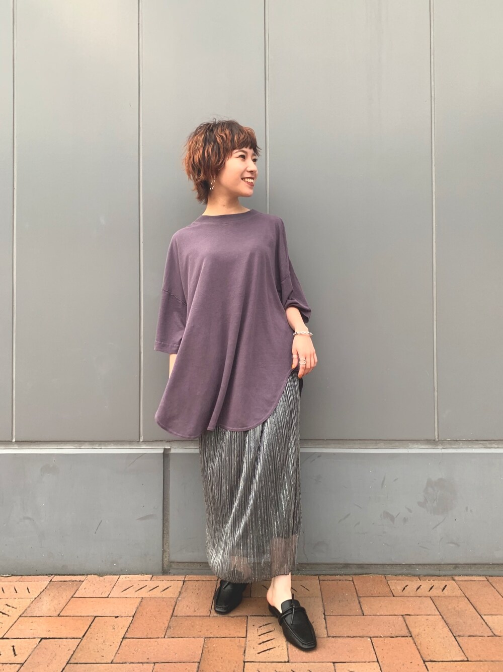 パープル系のTシャツ/カットソー、シルバー系のスカート、ブラック系のスリッポンを着用したレディースの夏コーディネートの1枚目の写真