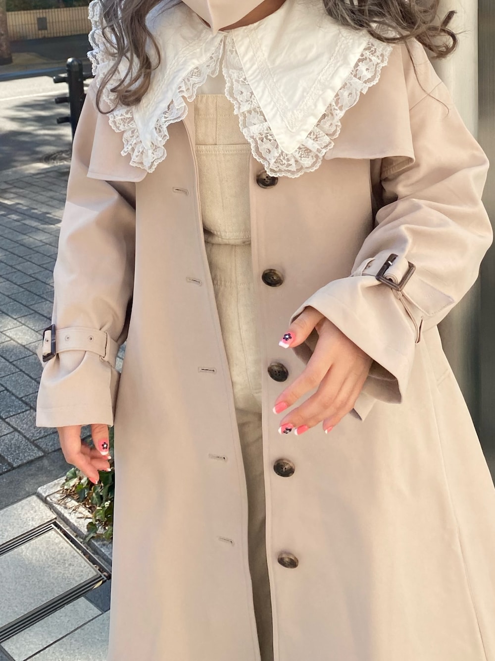 ベージュ系のトレンチコートを着用したレディースの冬コーディネートの1枚目の写真