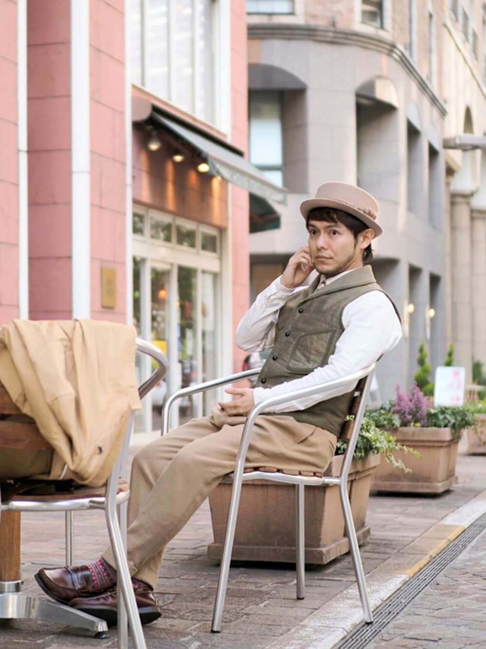 ベージュ系のステンカラーコート、ホワイト系のシャツ/ブラウス、グリーン系のベストを着用したメンズの冬コーディネートの1枚目の写真