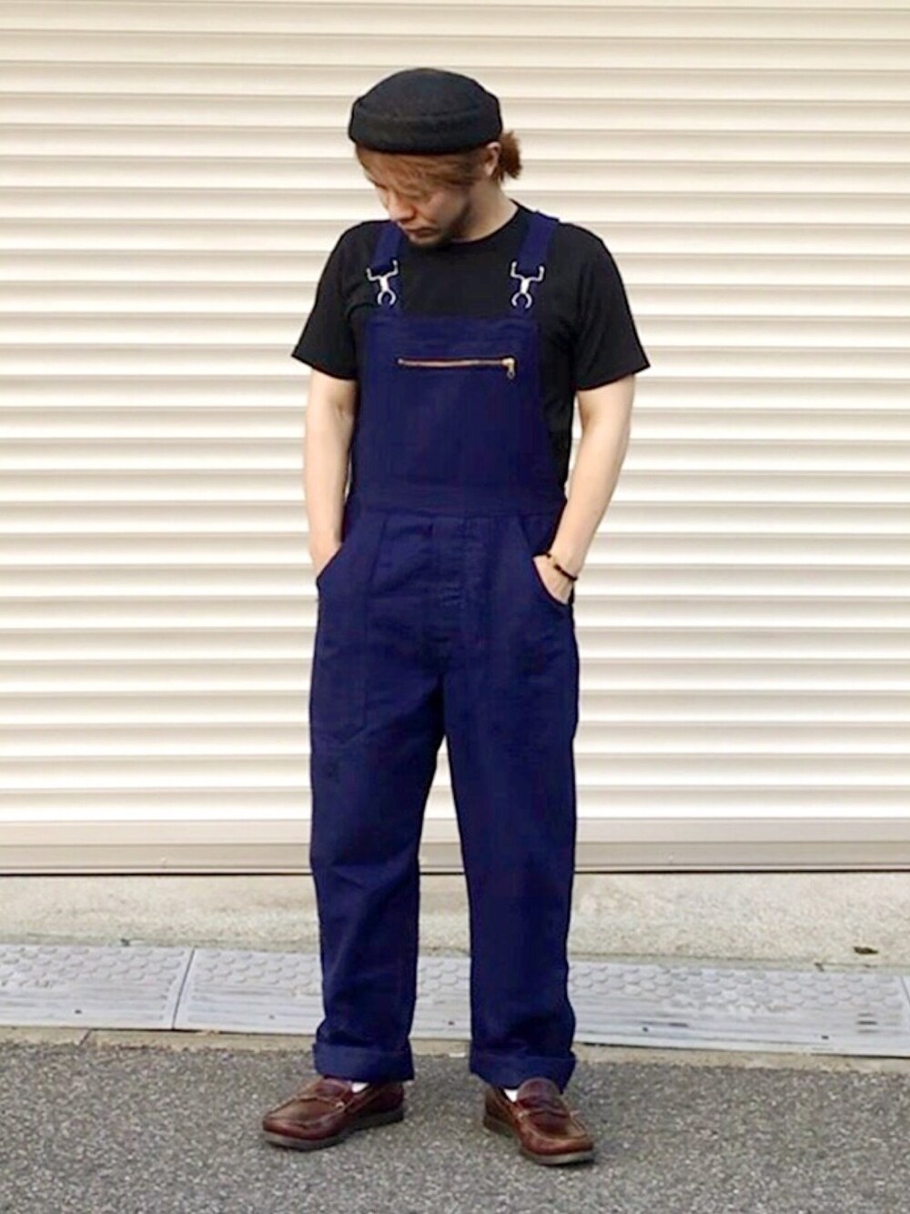 ブラック系のTシャツ/カットソー、ブルー系のサロペット/オーバーオール、ブラウン系のモカシン/デッキシューズを着用したメンズの夏コーディネートの1枚目の写真