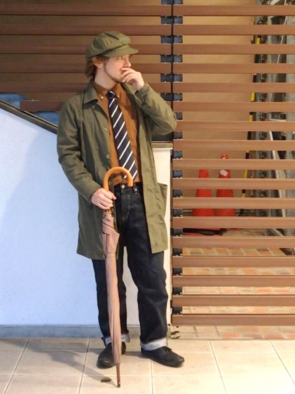 グリーン系のステンカラーコート、ブルー系のネクタイ、ブラウン系のシャツ/ブラウスを着用したメンズの秋コーディネートの1枚目の写真