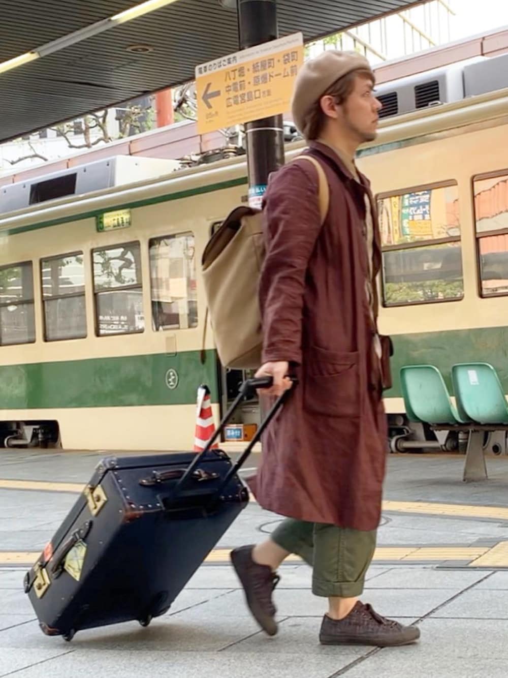 ブルー系のスーツケース/キャリーバッグ、ベージュ系のバックパック/リュック、グリーン系のチノパンツを着用したメンズの春コーディネートの1枚目の写真