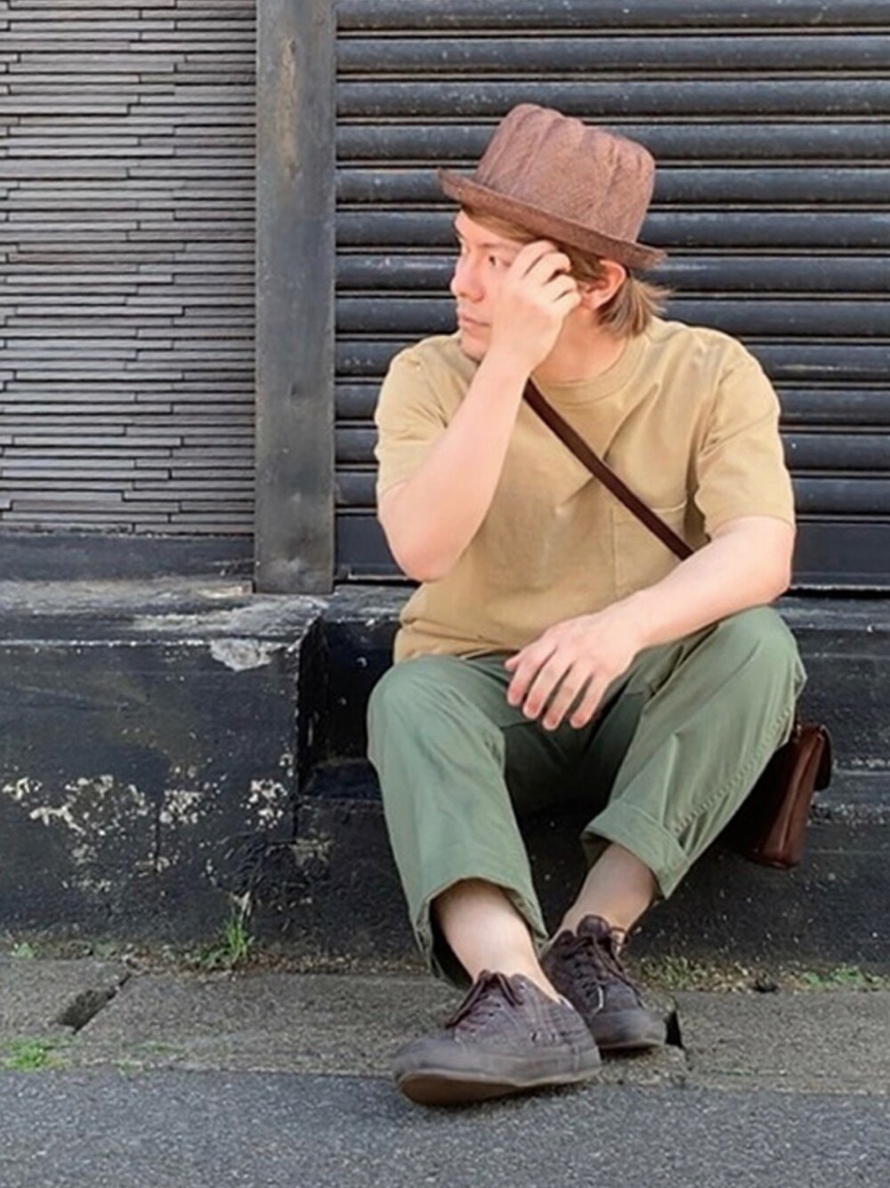 グリーン系のチノパンツ、ブラウン系のスニーカー、ブラウン系のショルダーバッグを着用したメンズの春コーディネートの1枚目の写真