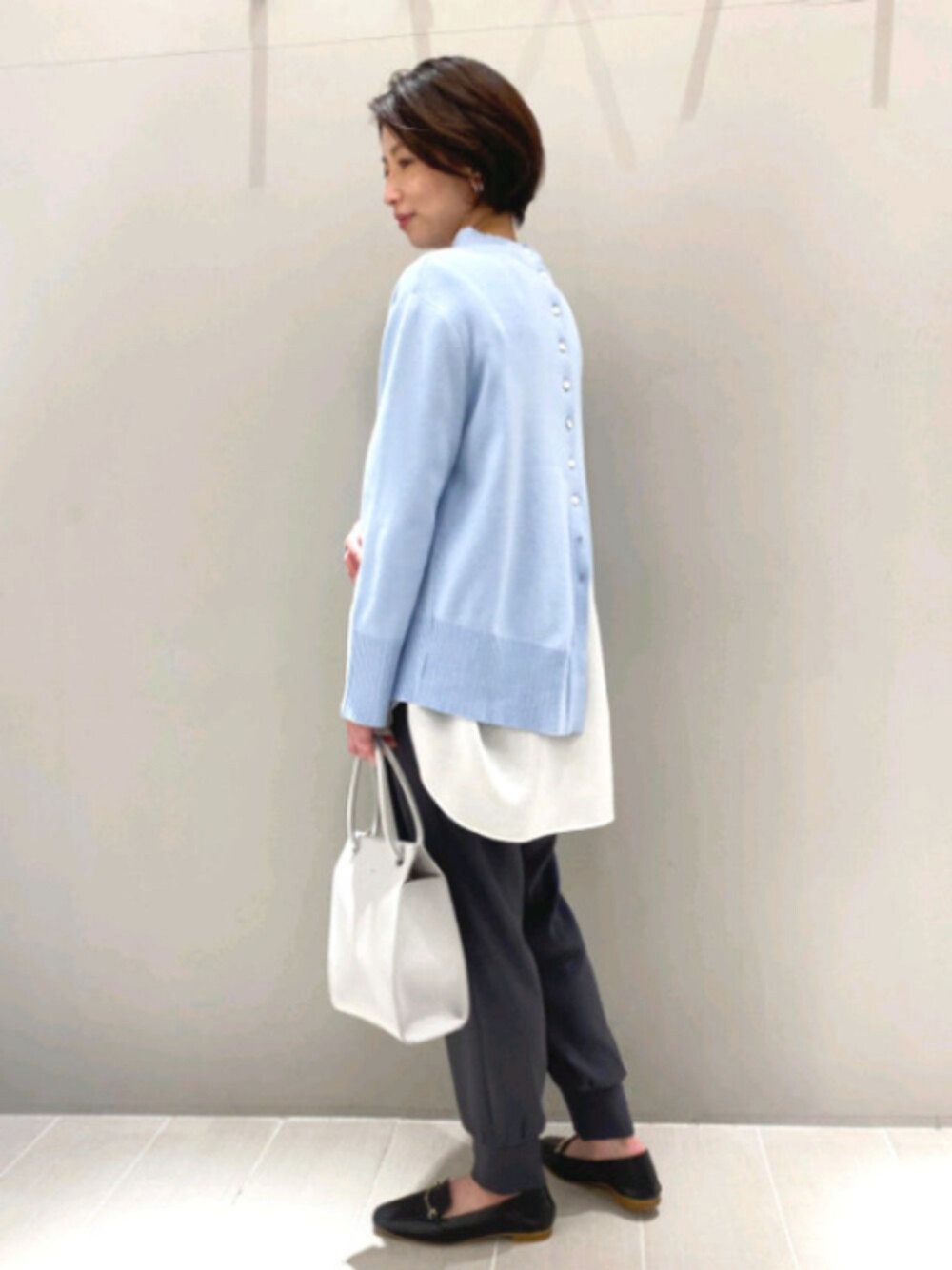 ブルー系のニット/セーター、ホワイト系のシャツ/ブラウス、ブラック系のその他パンツを着用したレディースの春コーディネートの1枚目の写真