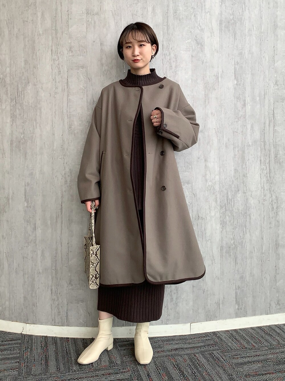 ブラウン系のワンピース、ブラウン系のその他アウター、ホワイト系のブーツを着用したレディースの冬コーディネートの1枚目の写真