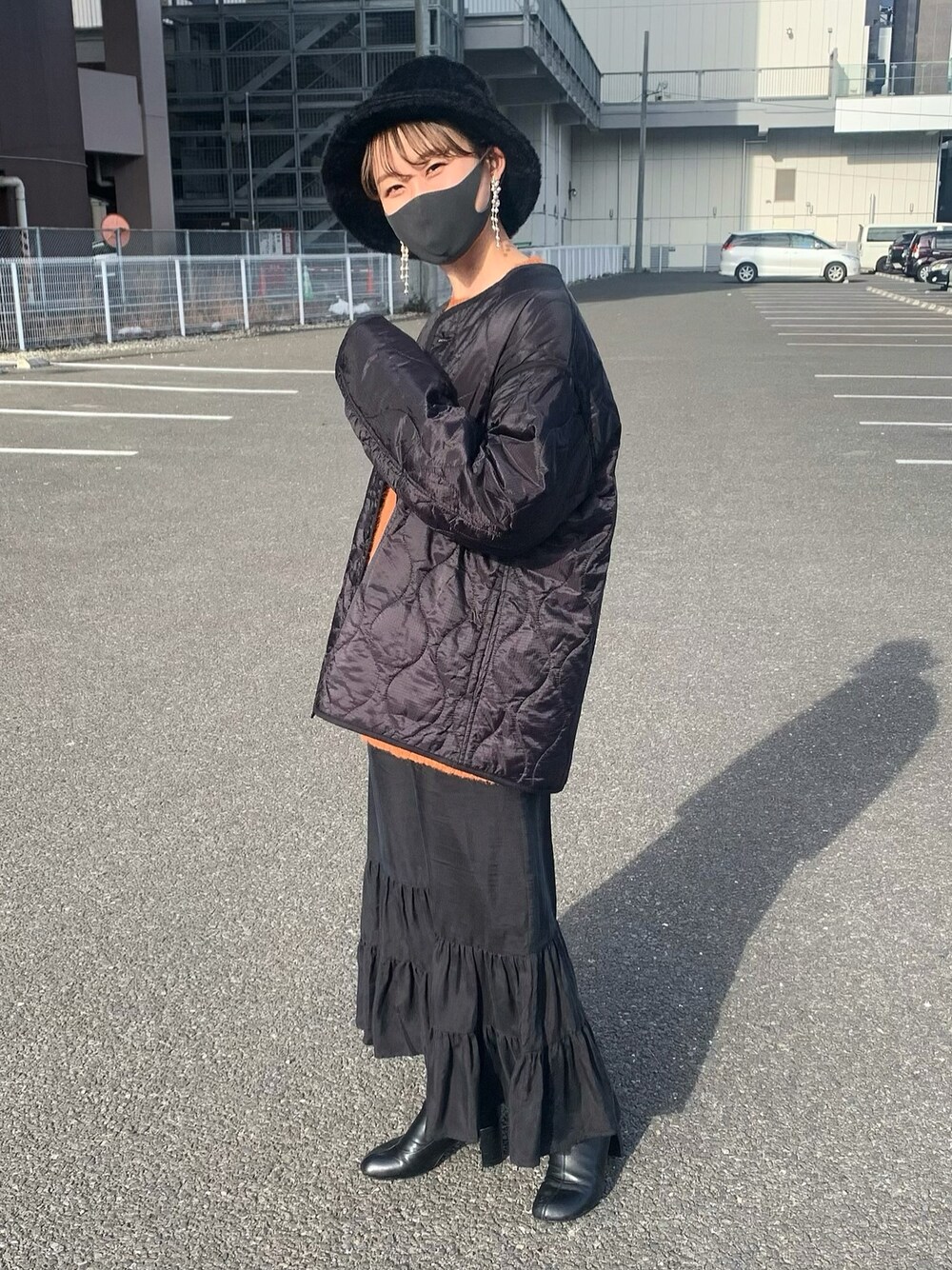 ブラック系のブルゾン、ブラック系のブーツ、オレンジ系のニット/セーターを着用したレディースの冬コーディネートの1枚目の写真