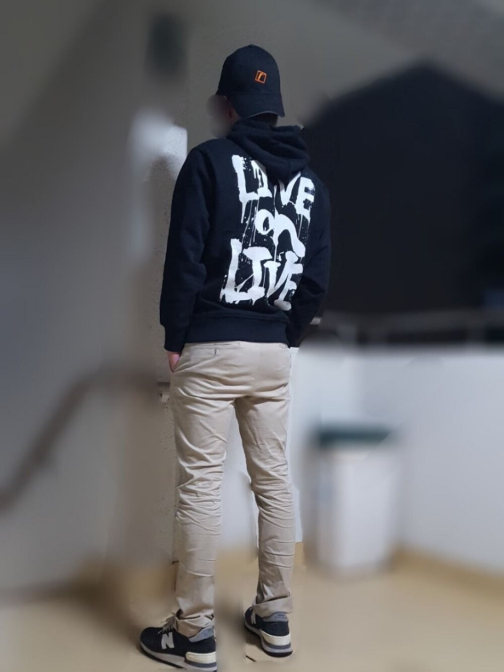 ブラック系のパーカー、ベージュ系のチノパンツ、ブルー系のスニーカーを着用したメンズの秋コーディネートの1枚目の写真