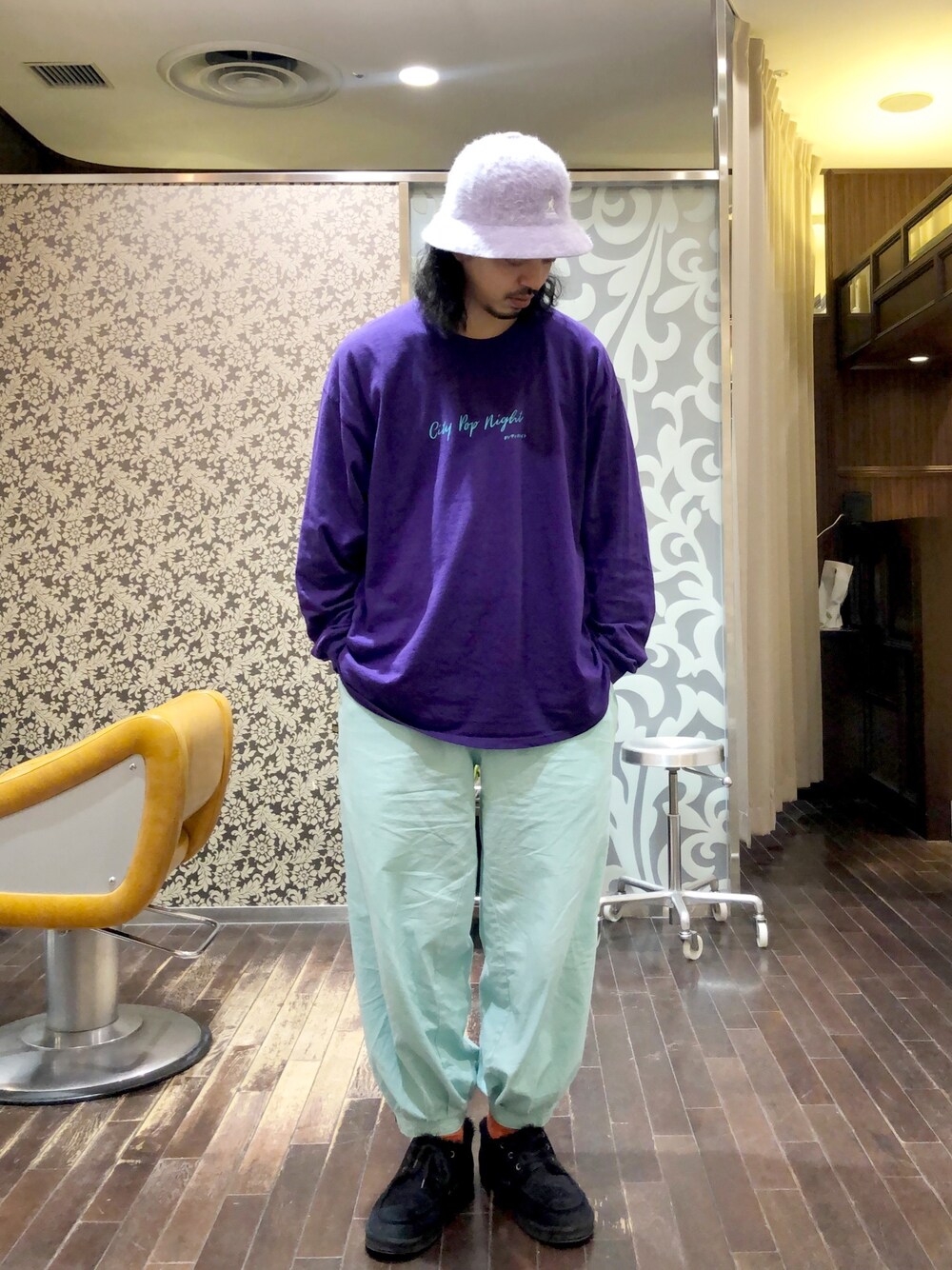 パープル系のTシャツ/カットソー、グリーン系のパンツ、ブラック系のシューズを着用したメンズの春コーディネートの1枚目の写真