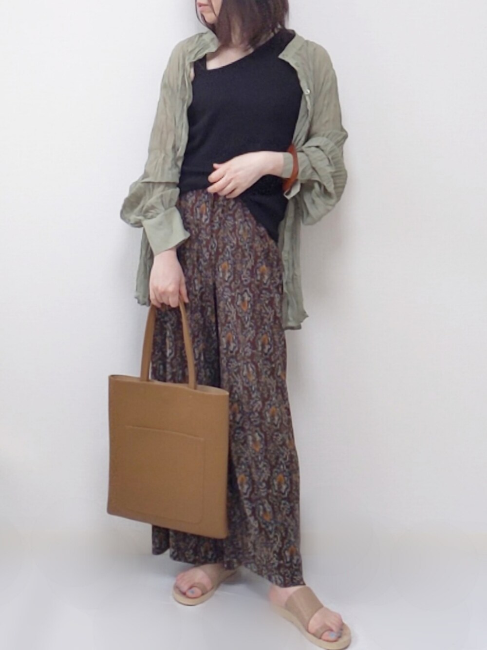 グリーン系のシャツ/ブラウス、ブラウン系のトートバッグ、ベージュ系のサンダルを着用したレディースの春コーディネートの1枚目の写真