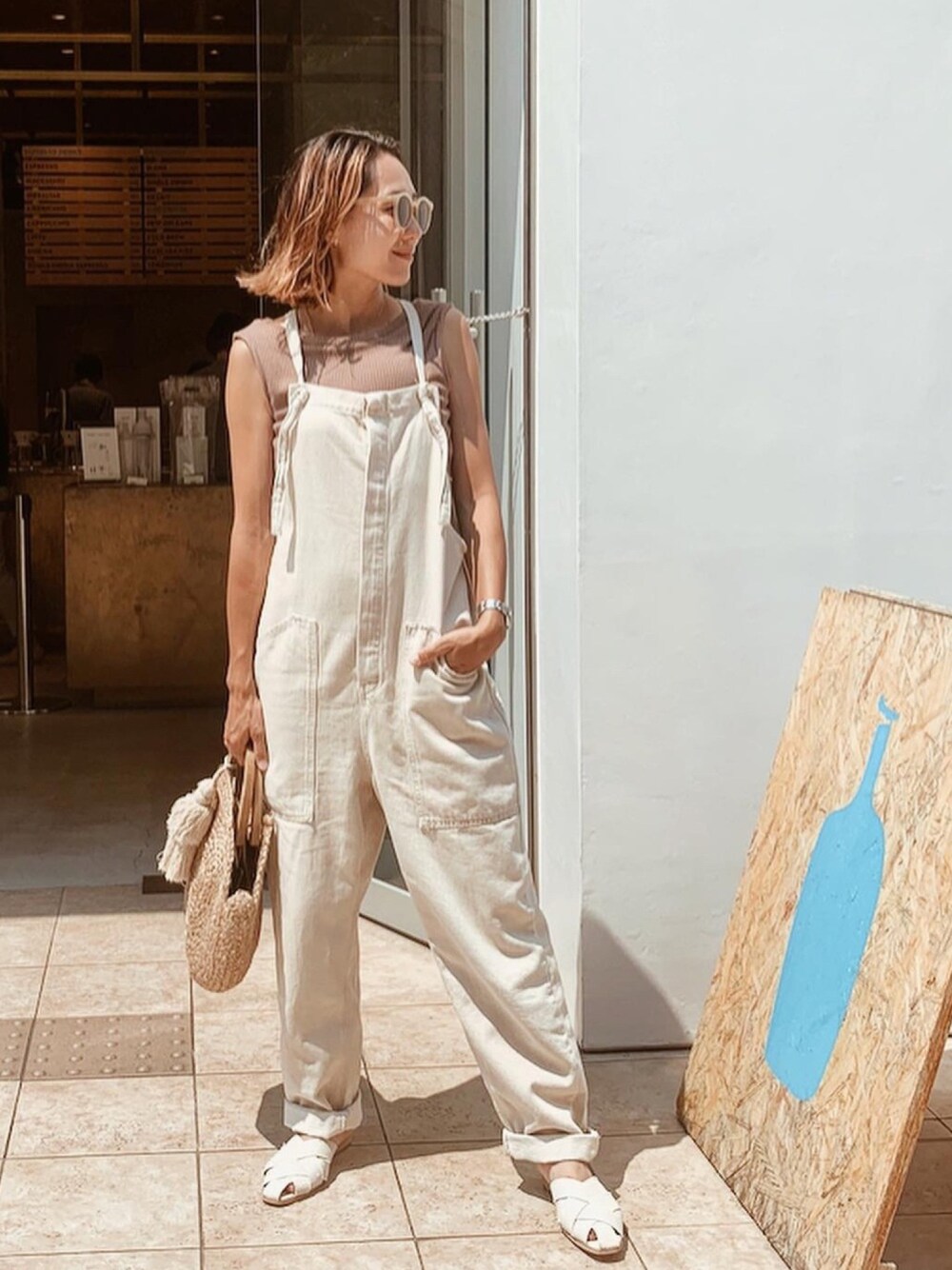 ベージュ系のサロペット/オーバーオール、ホワイト系のサンダル、ベージュ系のショルダーバッグを着用したレディースの夏コーディネートの1枚目の写真