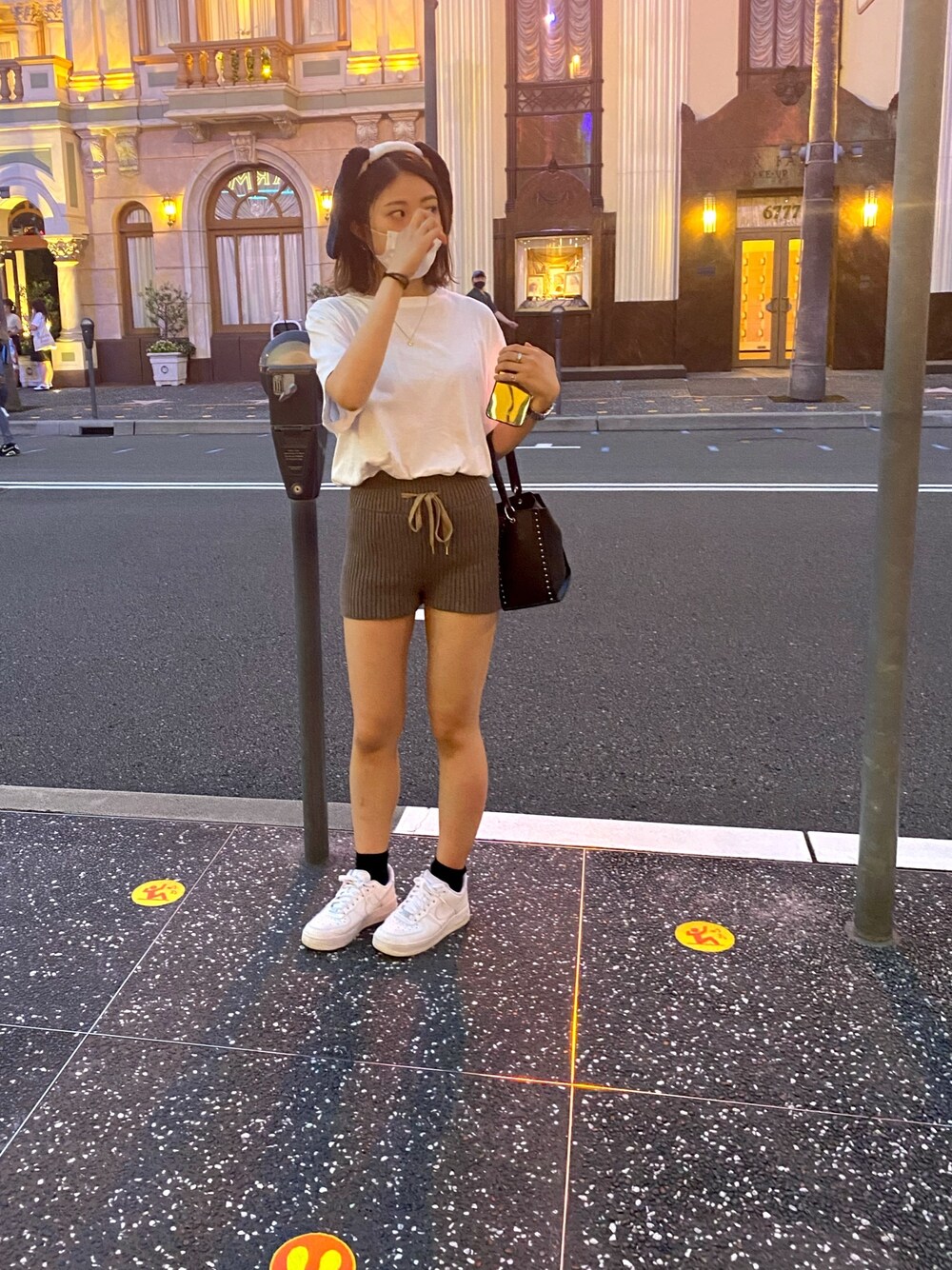 ブラウン系のパンツ、ホワイト系のスニーカー、ブラック系のショルダーバッグを着用したレディースの夏コーディネートの1枚目の写真