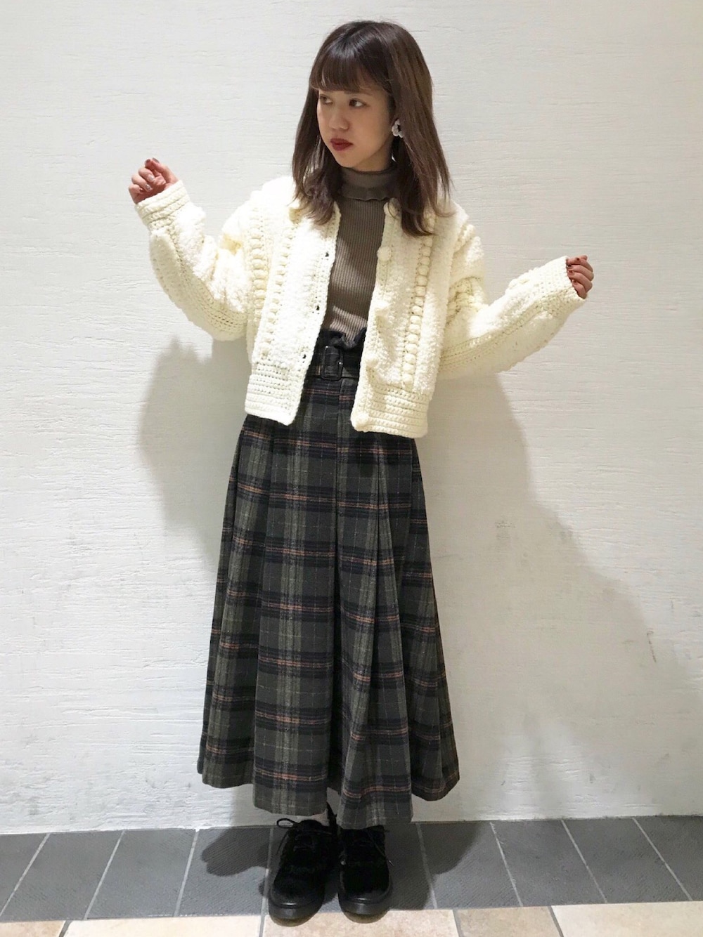 グリーン系のスカート、ベージュ系のニット/セーター、ホワイト系のその他アウターを着用したレディースの秋コーディネートの1枚目の写真