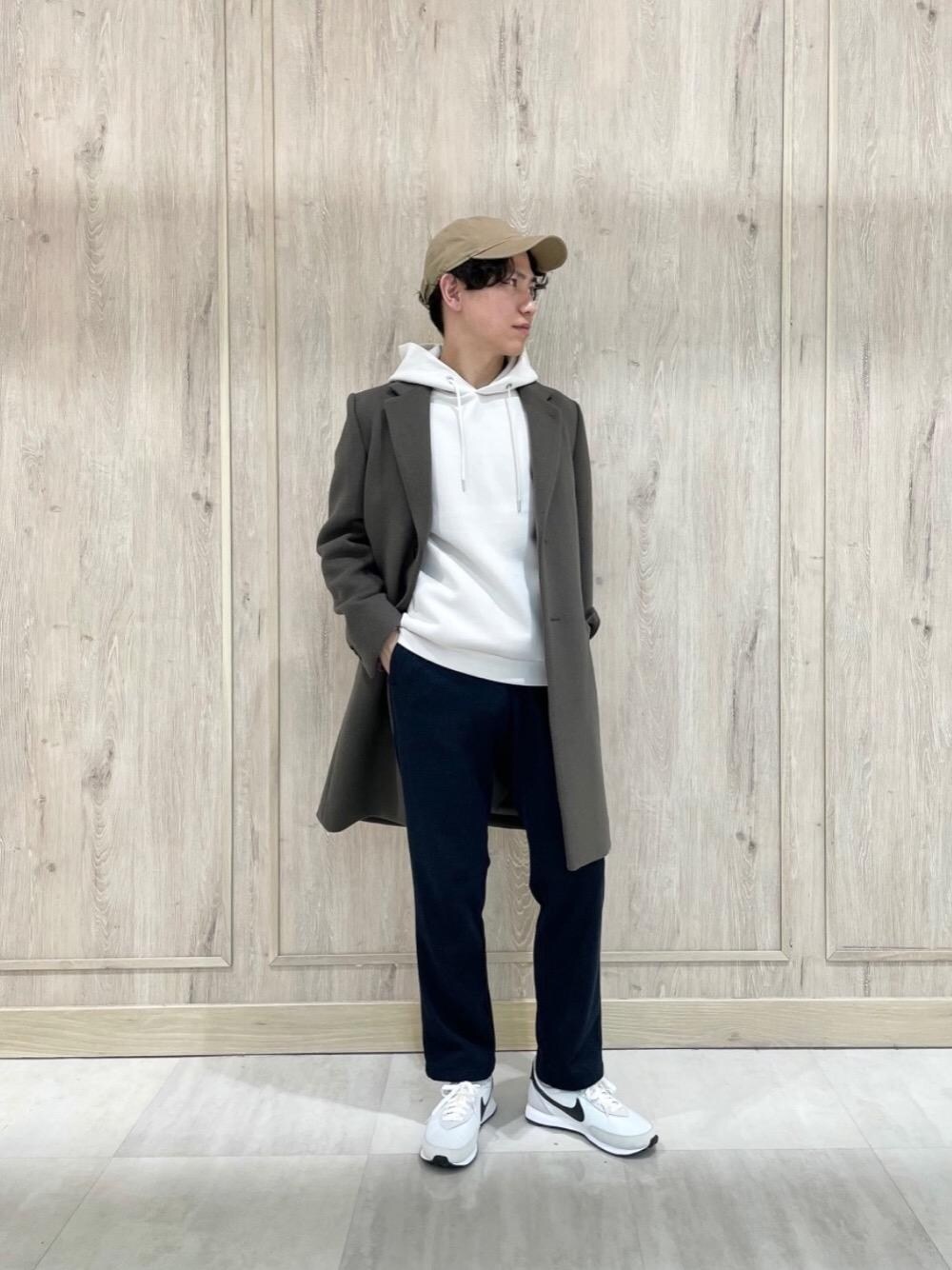 グリーン系のチェスターコート、グレー系のパーカー、ホワイト系のスニーカーを着用したメンズの冬コーディネートの1枚目の写真