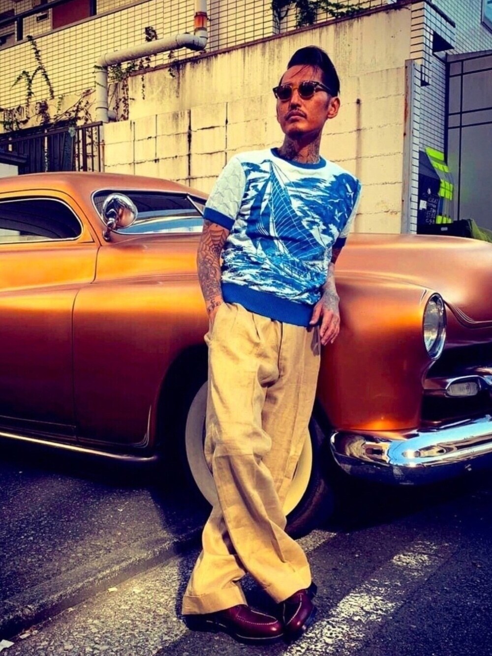 ブルー系のニット/セーター、ベージュ系のスラックス、ブラウン系のスリッポンを着用したメンズの春コーディネートの1枚目の写真