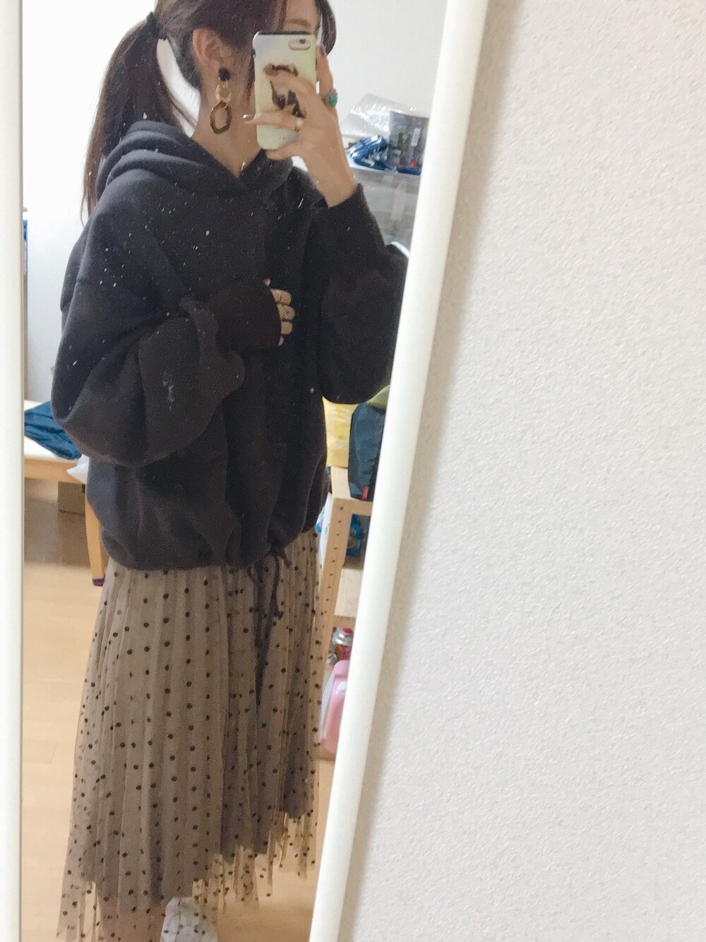 グレー系のパーカー、ブラウン系のスカート、ブラウン系のイヤリングを着用したレディースの秋コーディネートの1枚目の写真