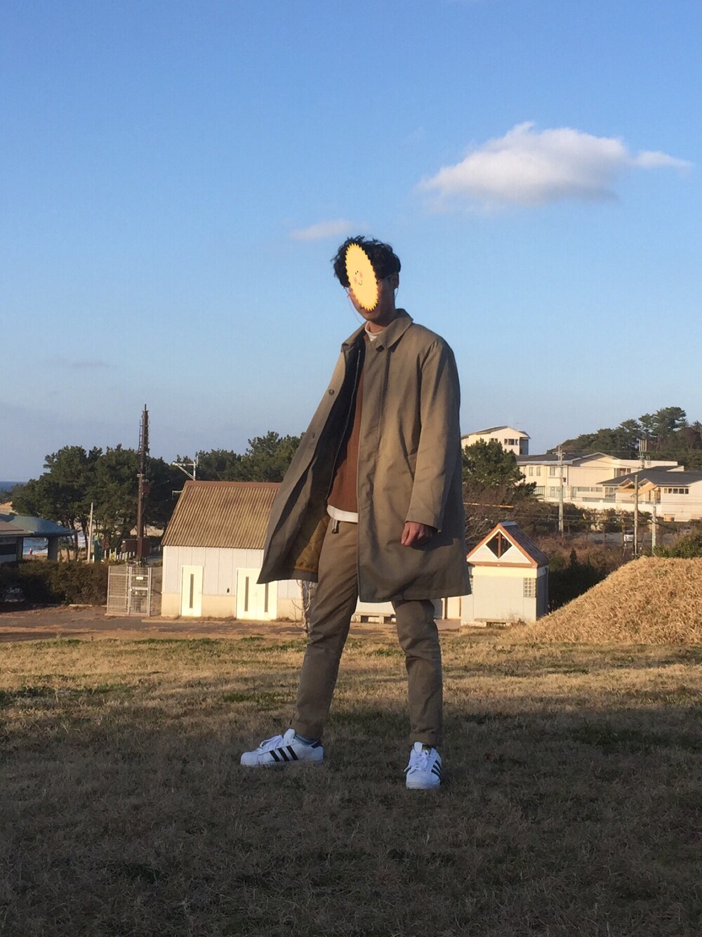 ホワイト系のスニーカー、ブラウン系のシャツ/ブラウス、ベージュ系のステンカラーコートを着用したメンズの冬コーディネートの1枚目の写真