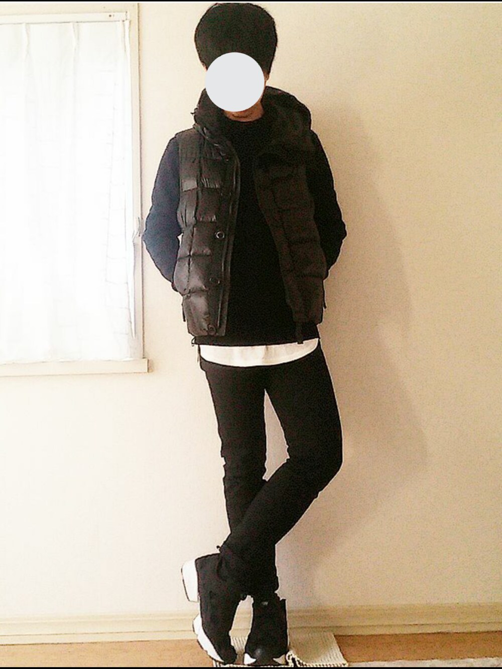 ブラック系のダウンベスト、ブラック系のニット/セーター、ホワイト系のTシャツ/カットソーを着用したメンズの冬コーディネートの1枚目の写真