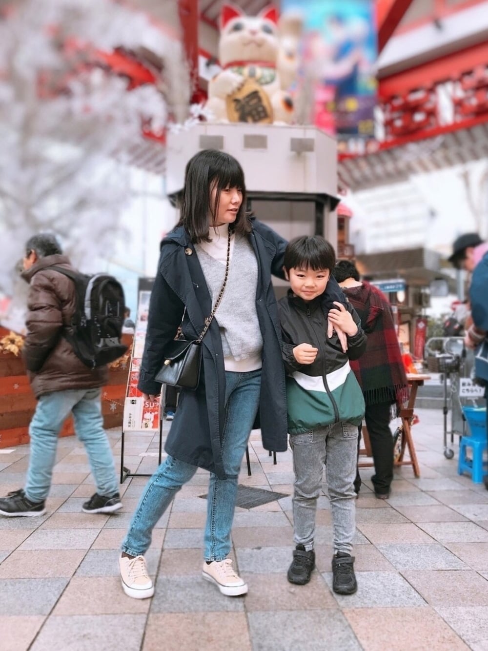 ブルー系のデニムパンツ、ブラック系のショルダーバッグ、ブルー系のトレンチコートを着用したレディースの冬コーディネートの1枚目の写真