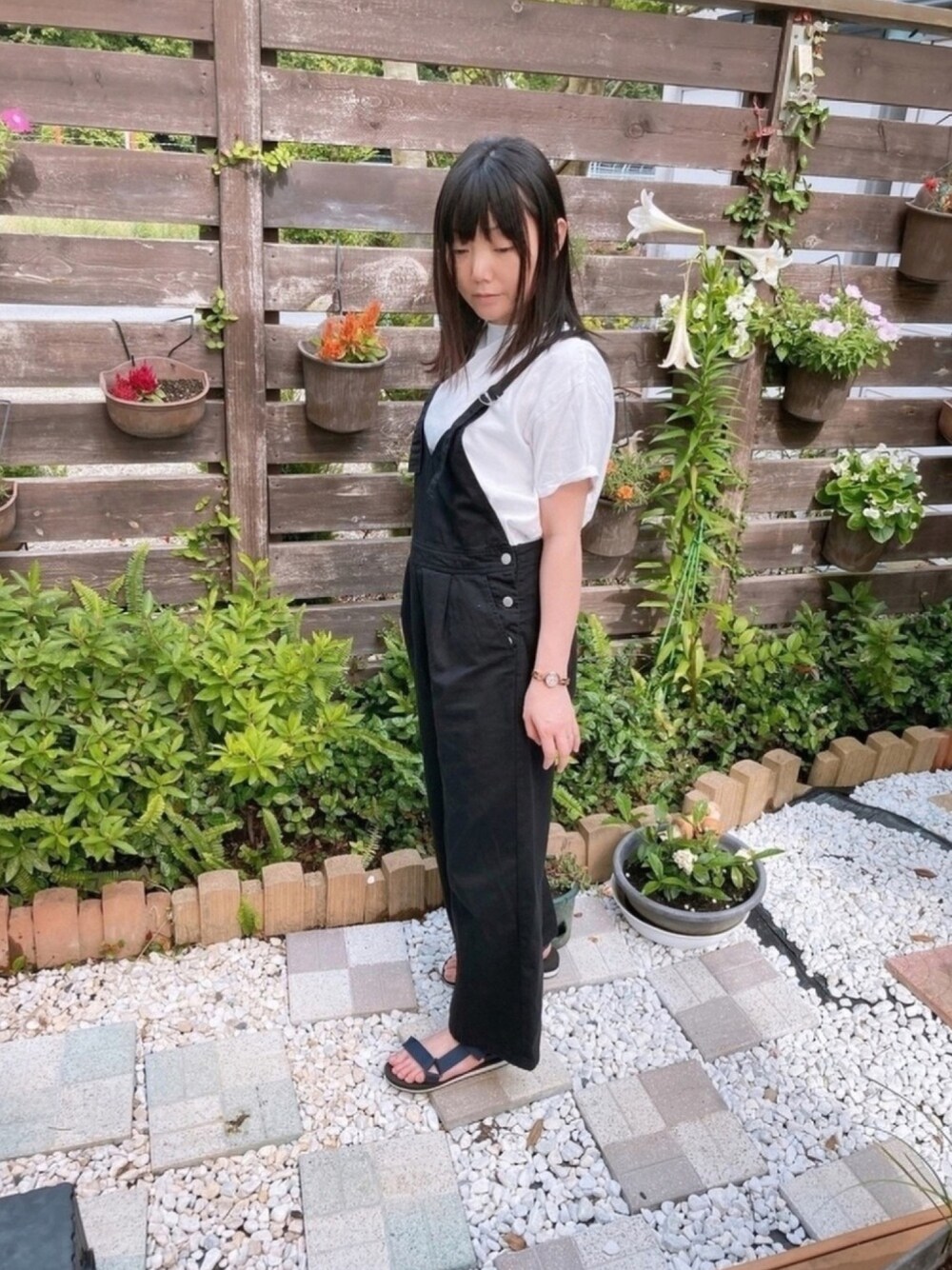 ブラック系のサロペット/オーバーオール、ブルー系のサンダル、ホワイト系のTシャツ/カットソーを着用したレディースの夏コーディネートの1枚目の写真