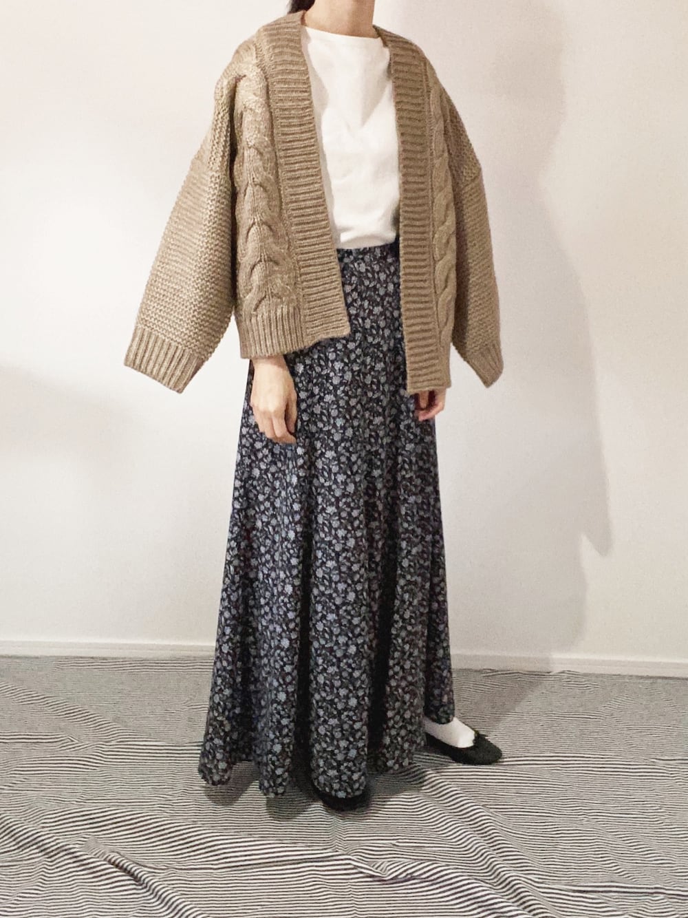 ブラウン系のカーディガン/ボレロ、ホワイト系のTシャツ/カットソー、ブラック系のスカートを着用したレディースの秋コーディネートの1枚目の写真