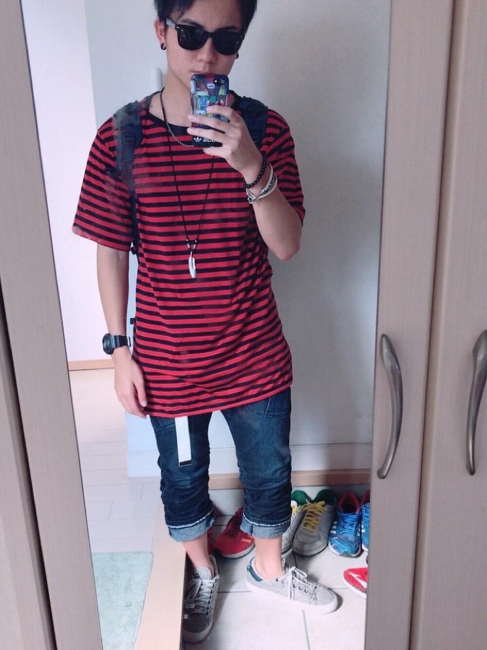 ホワイト系のスニーカー、ブルー系のデニムパンツ、レッド系のTシャツ/カットソーを着用したメンズの秋コーディネートの1枚目の写真
