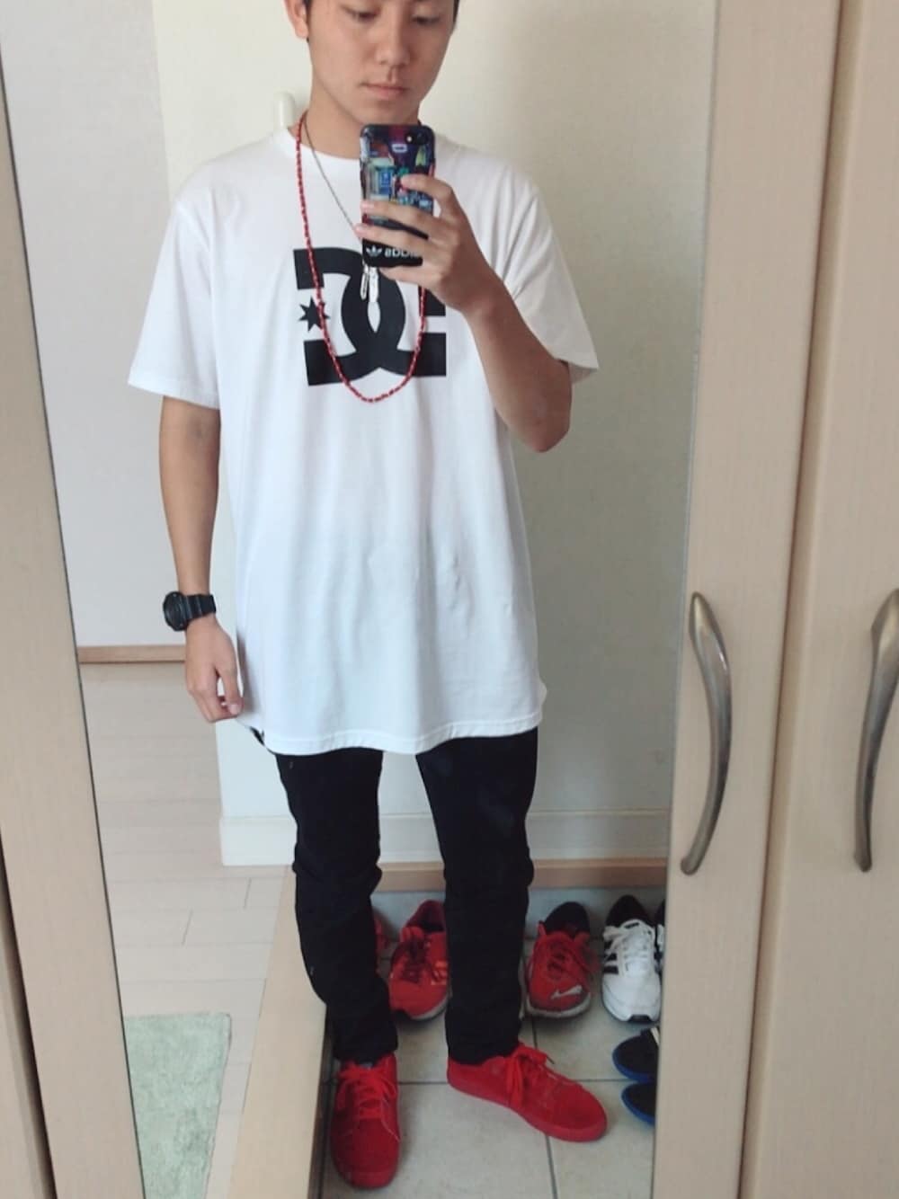 ブラック系のパンツ、ホワイト系のTシャツ/カットソー、レッド系のスニーカーを着用したメンズの秋コーディネートの1枚目の写真