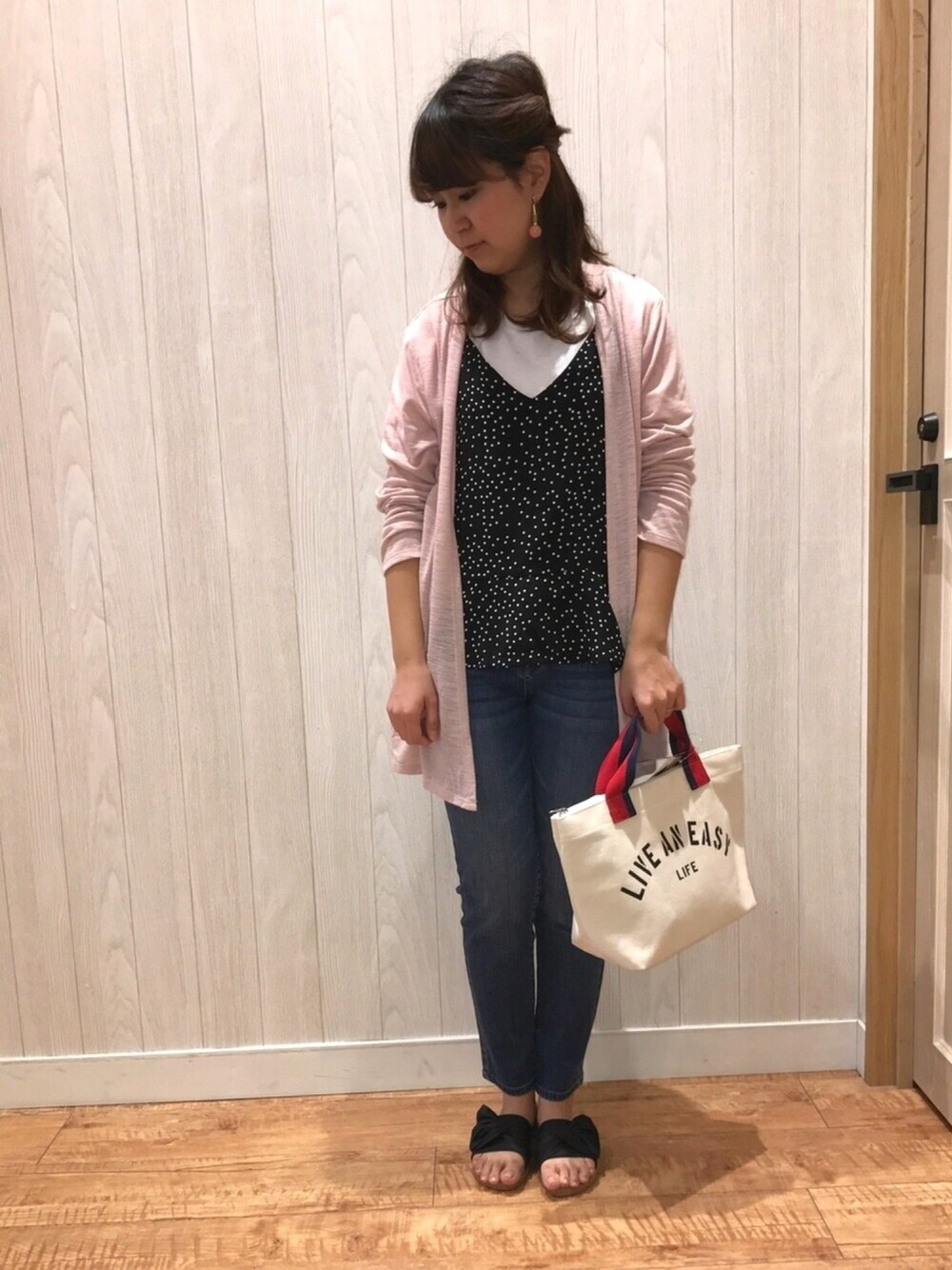 ブラック系のタンクトップ、ピンク系のカーディガン/ボレロ、ブルー系のデニムパンツを着用したレディースの春コーディネートの1枚目の写真