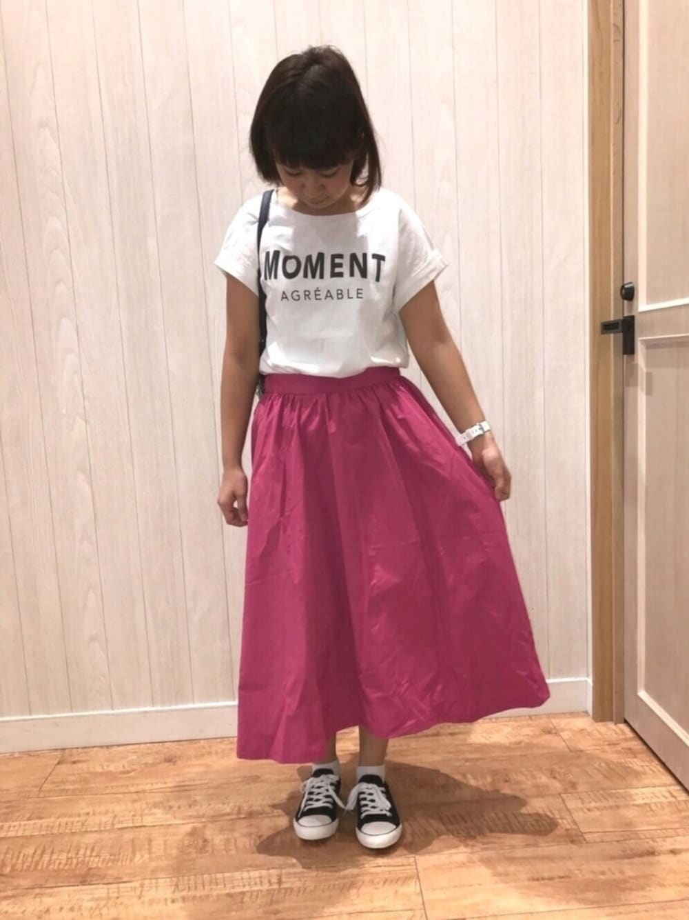 ブラック系のスニーカー、ブルー系のショルダーバッグ、ピンク系のスカートを着用したレディースの春コーディネートの1枚目の写真