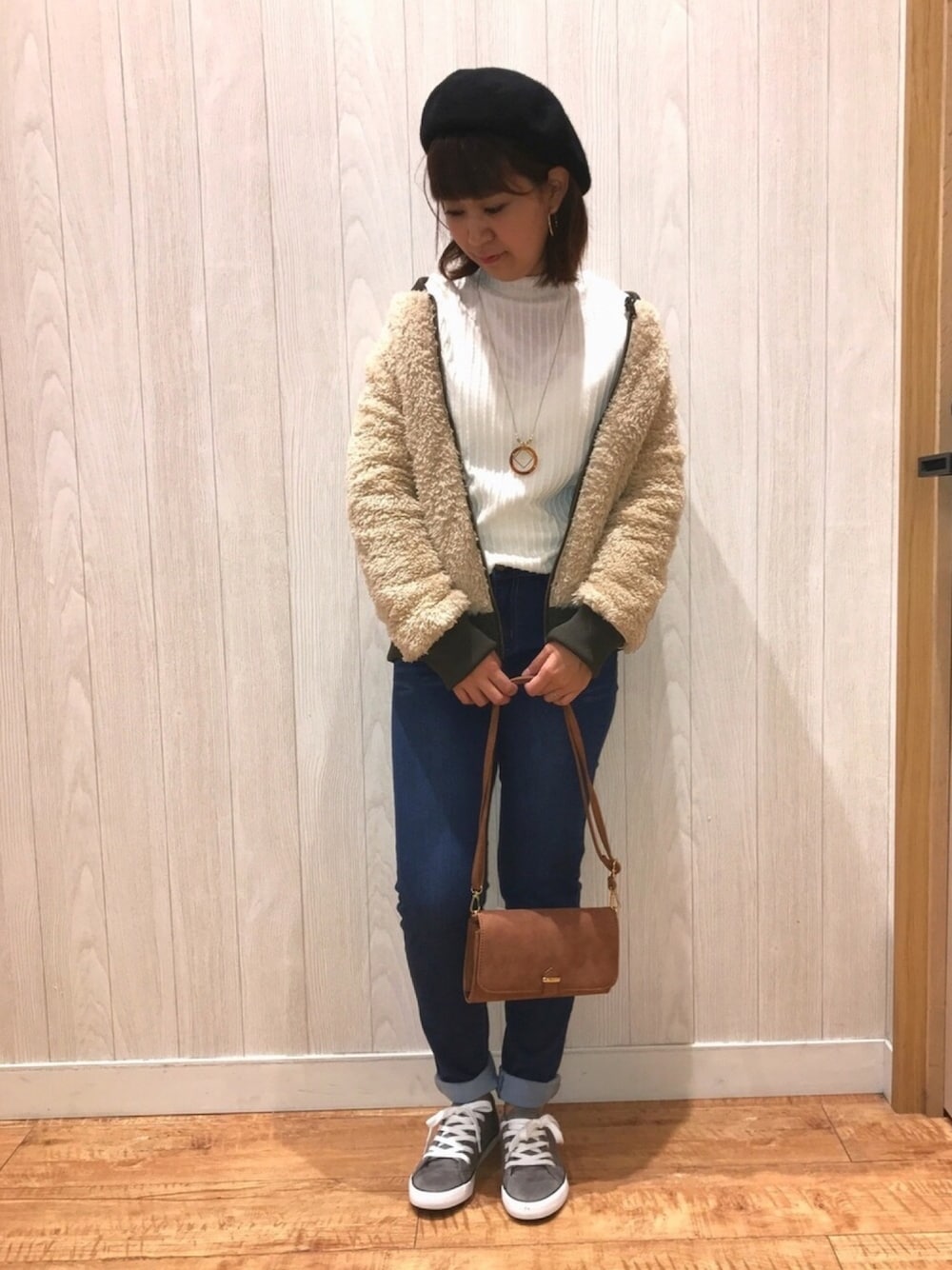 ブルー系のデニムパンツ、グレー系のスニーカー、ブラウン系のバッグを着用したレディースの秋コーディネートの1枚目の写真