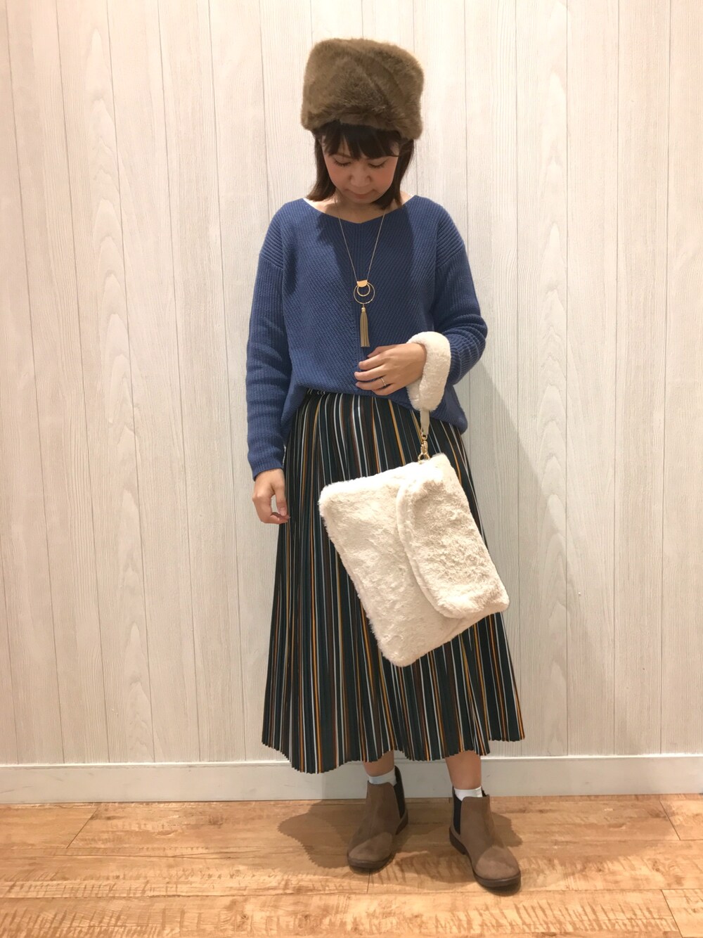 ブルー系のニット/セーター、グリーン系のスカート、ブラウン系のブーツを着用したレディースの秋コーディネートの1枚目の写真