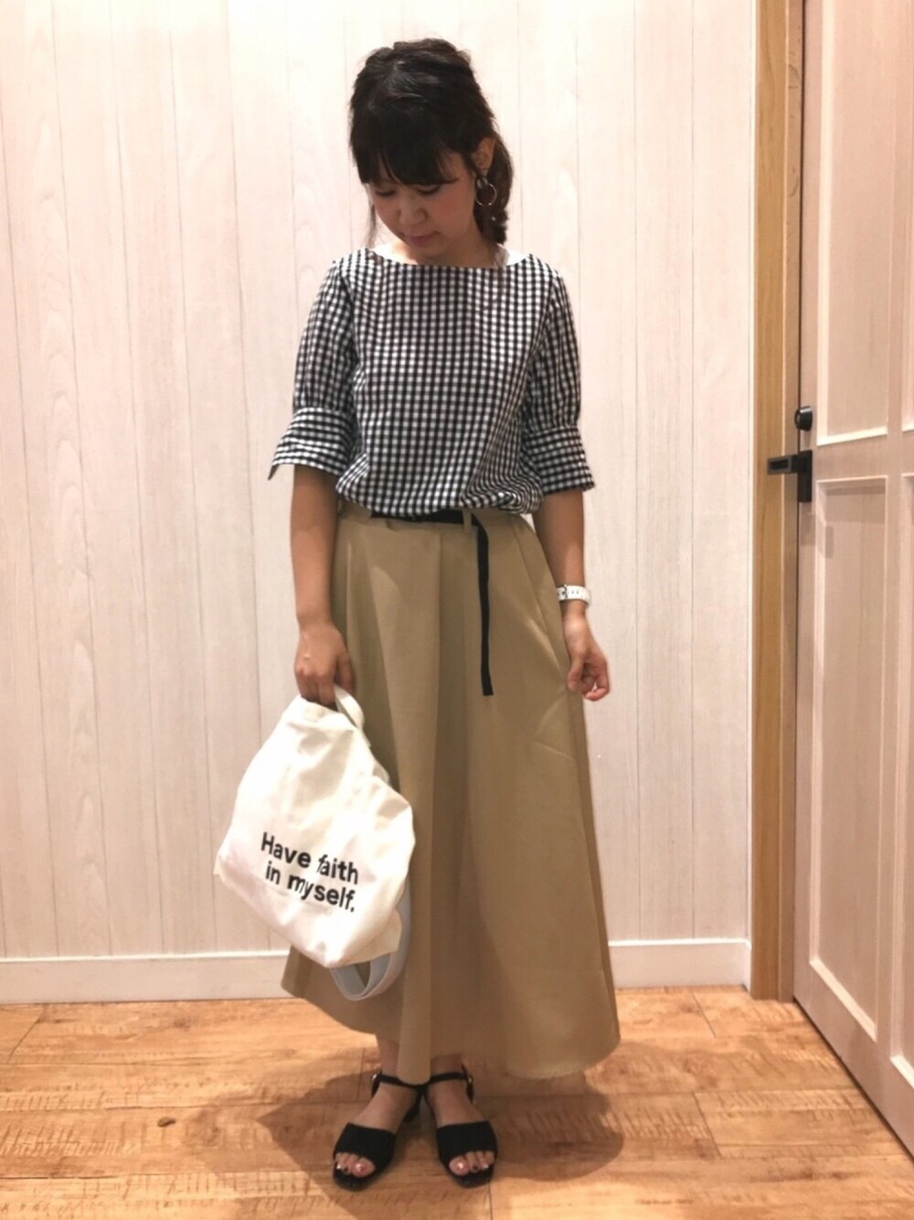 ブラック系のシャツ/ブラウス、ベージュ系のスカート、ブラック系のサンダルを着用したレディースの夏コーディネートの1枚目の写真