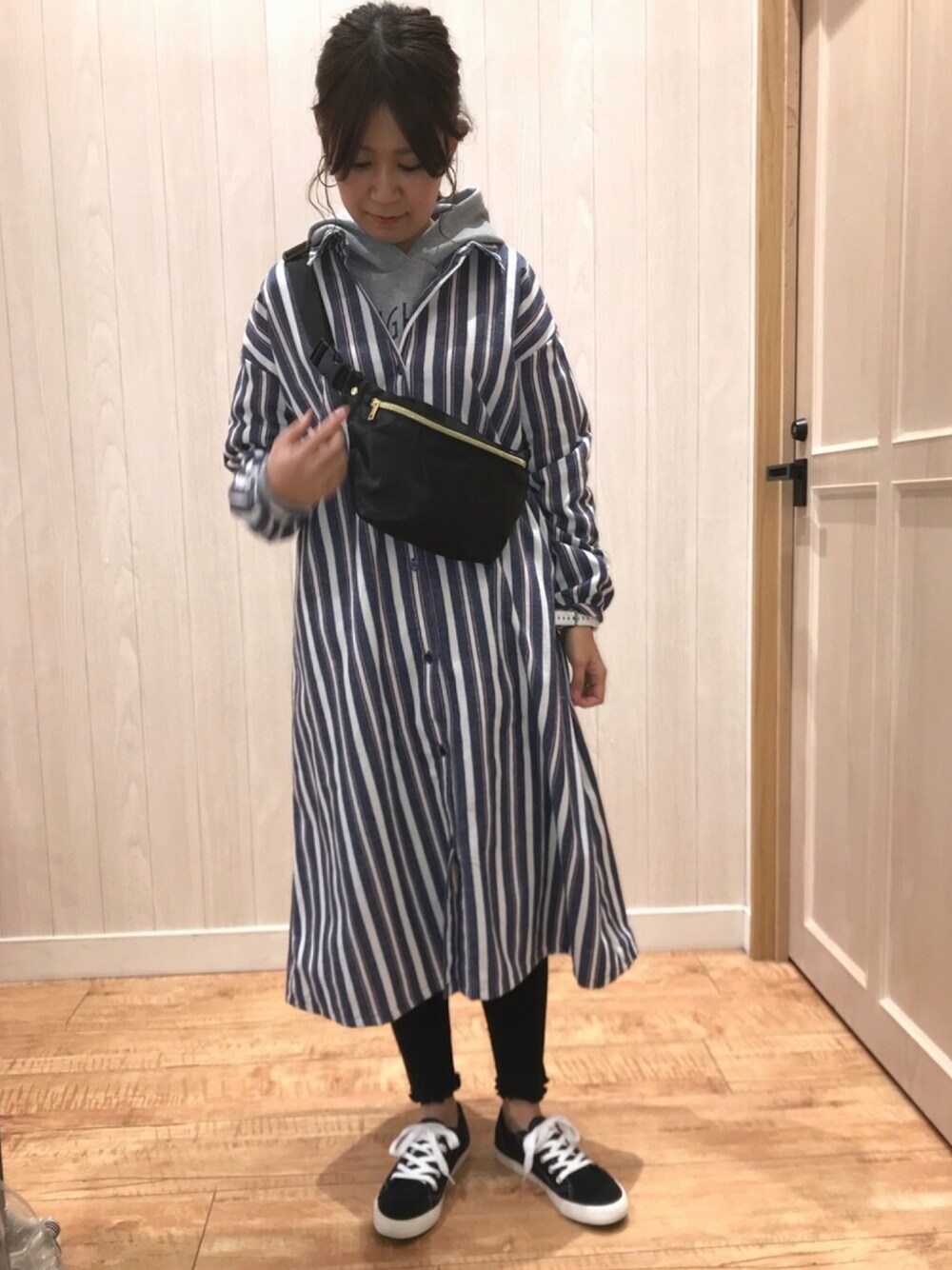 ベージュ系のワンピース、グレー系のパーカー、ブラック系のスニーカーを着用したレディースの冬コーディネートの1枚目の写真