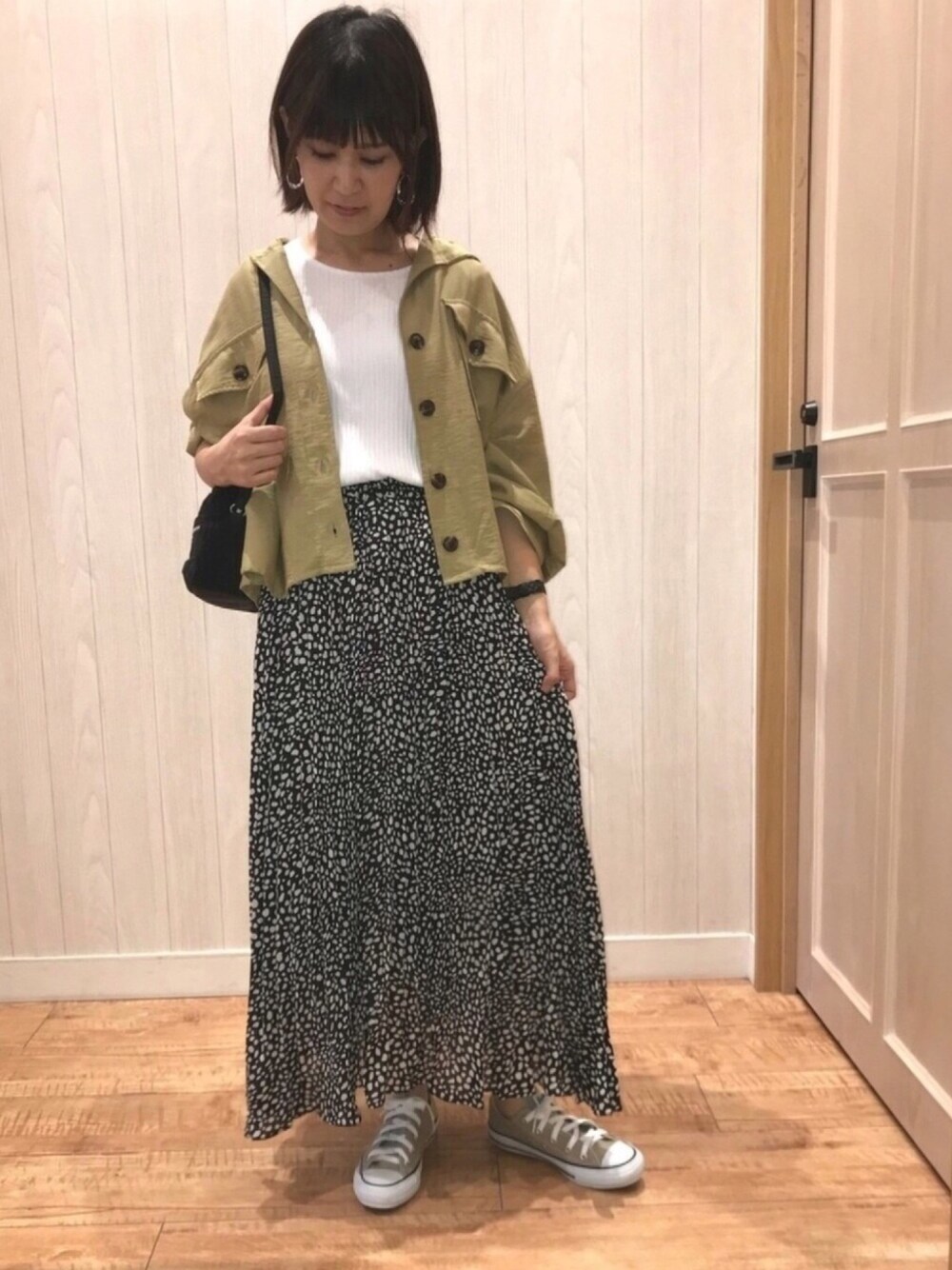 ベージュ系のトップス、ホワイト系のTシャツ/カットソー、ブラック系のショルダーバッグを着用したレディースの夏コーディネートの1枚目の写真