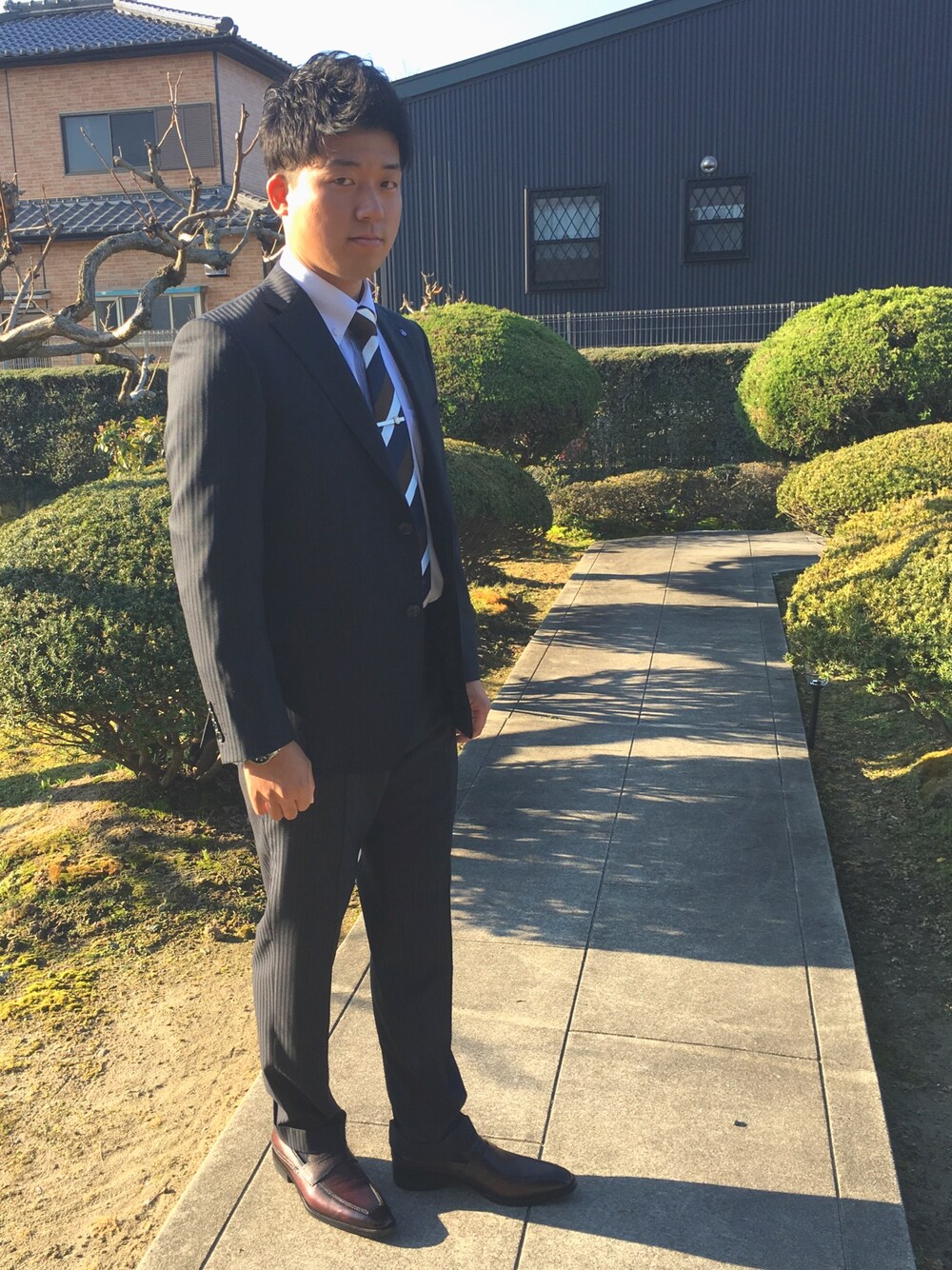 ブラウン系のネクタイ、ブルー系のスーツジャケット、シルバー系のアナログ腕時計を着用したメンズの春コーディネートの1枚目の写真