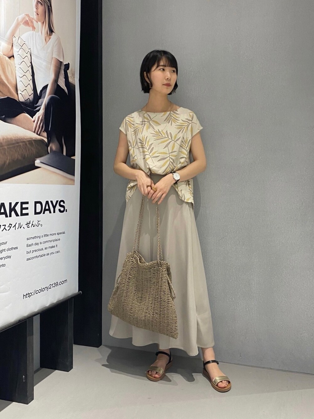 ベージュ系のスカート、ベージュ系のショルダーバッグ、ゴールド系のサンダルを着用したレディースの夏コーディネートの1枚目の写真