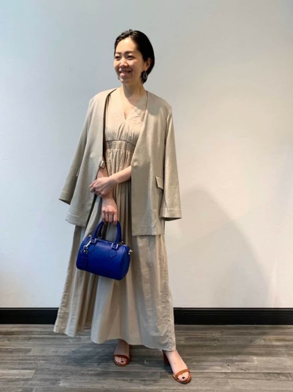 ベージュ系のワンピース、ベージュ系のノーカラージャケット、ブルー系のショルダーバッグを着用したレディースの春コーディネートの1枚目の写真