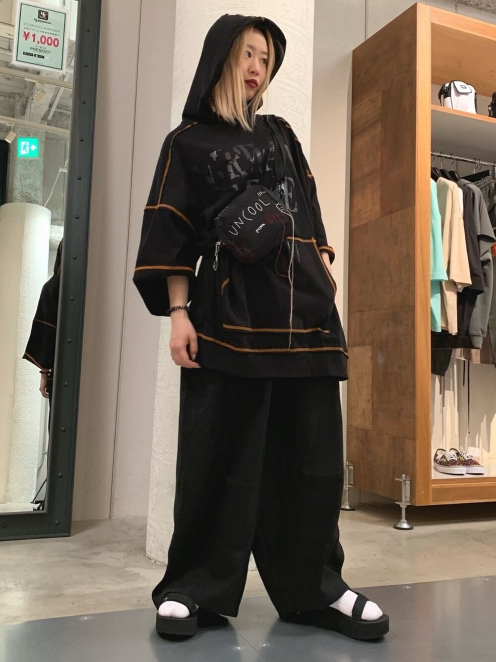 ブラック系のショルダーバッグ、ブラック系のその他パンツ、オレンジ系のパーカーを着用したレディースの春コーディネートの1枚目の写真