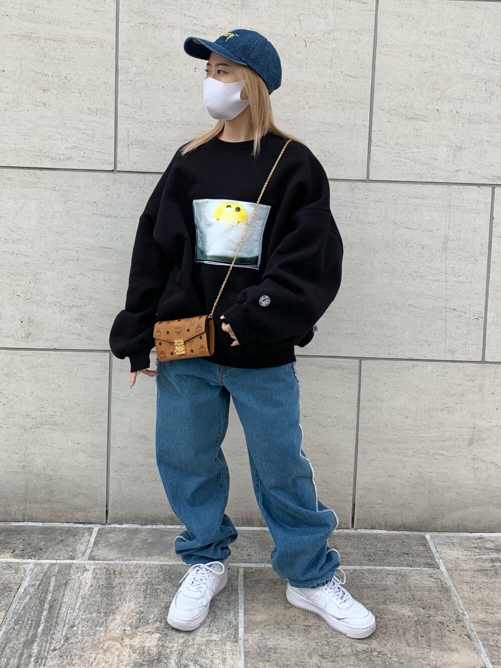 ブラック系のスウェット、ブルー系のキャップ、ブラウン系の財布を着用したレディースの秋コーディネートの1枚目の写真