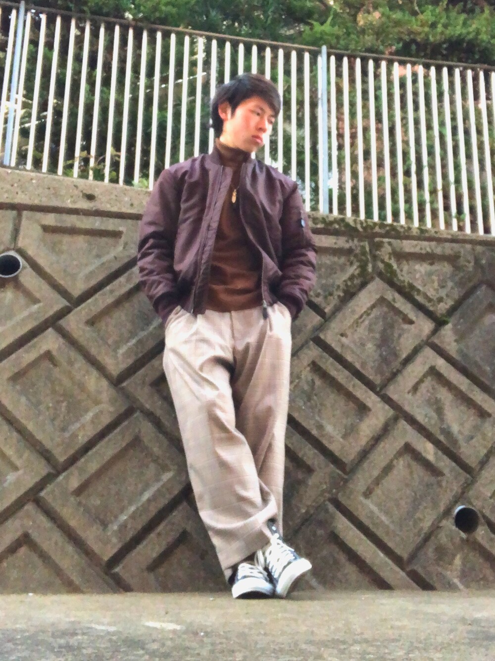 ブラック系のニット/セーター、ブラウン系のスラックス、グレー系のスニーカーを着用したメンズの冬コーディネートの1枚目の写真