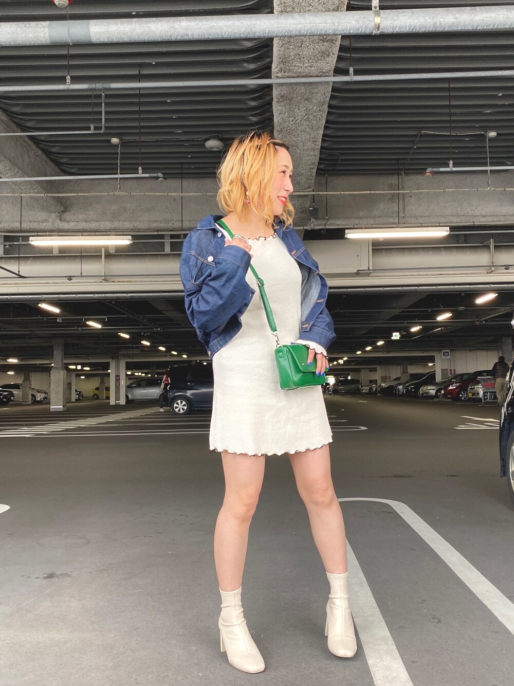 ブルー系のデニムジャケット、グリーン系のショルダーバッグ、ホワイト系のブーツを着用したレディースの春コーディネートの1枚目の写真