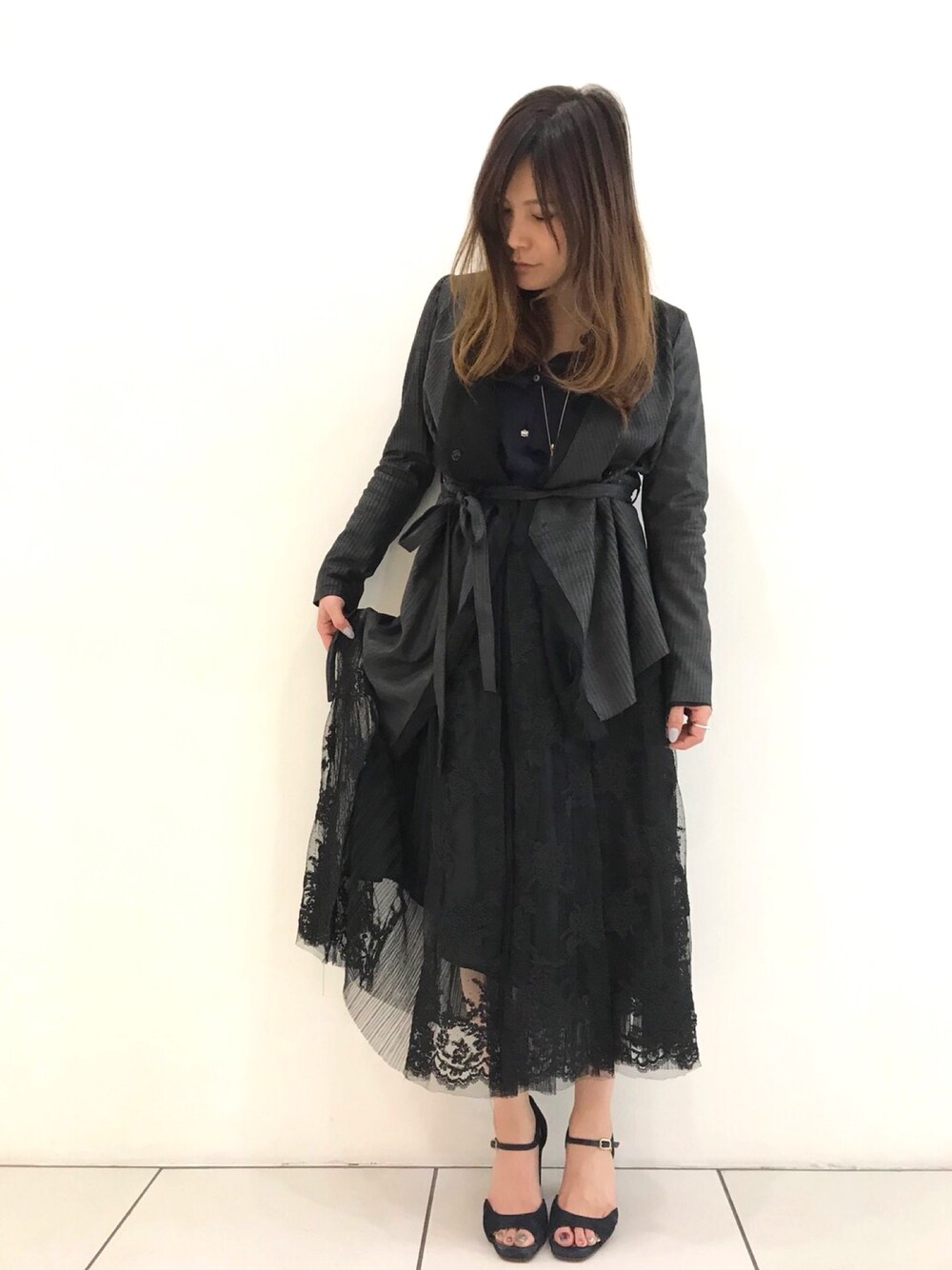 ブラック系のカーディガン/ボレロ、ブラック系のスカート、ブルー系のサンダルを着用したレディースの春コーディネートの1枚目の写真