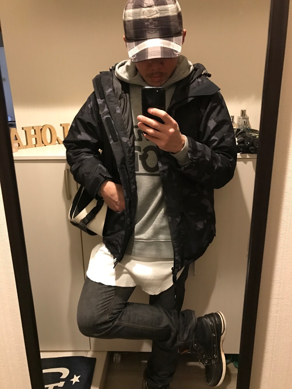 ブラック系のナイロンジャケット、グレー系のパーカー、ブラック系のデニムパンツを着用したメンズの冬コーディネートの1枚目の写真