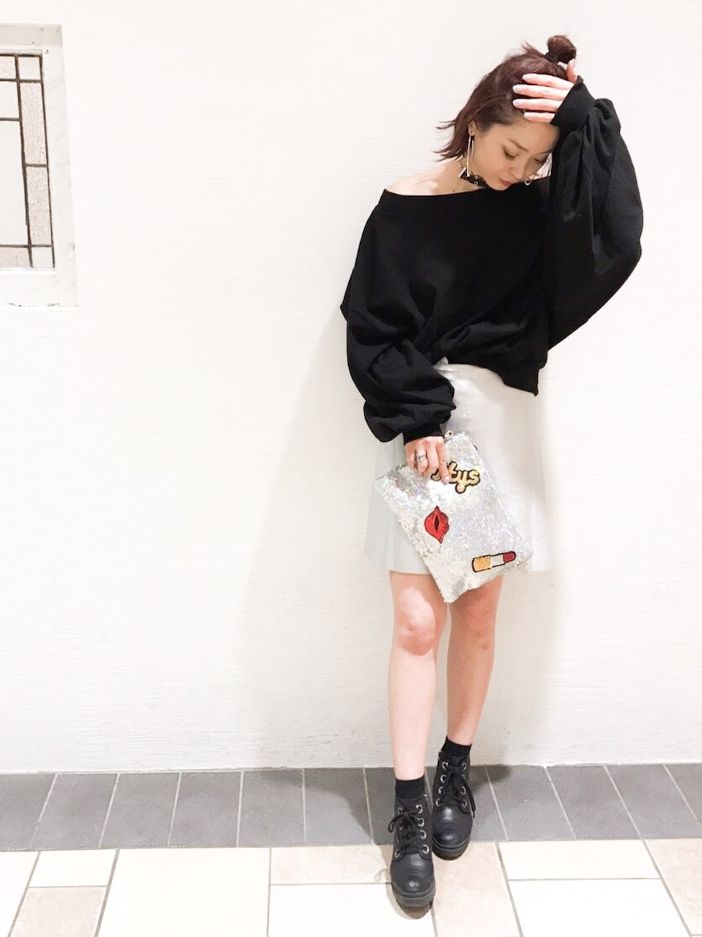 ブラック系のスウェット、シルバー系のスカート、シルバー系のクラッチバッグを着用したレディースの春コーディネートの1枚目の写真